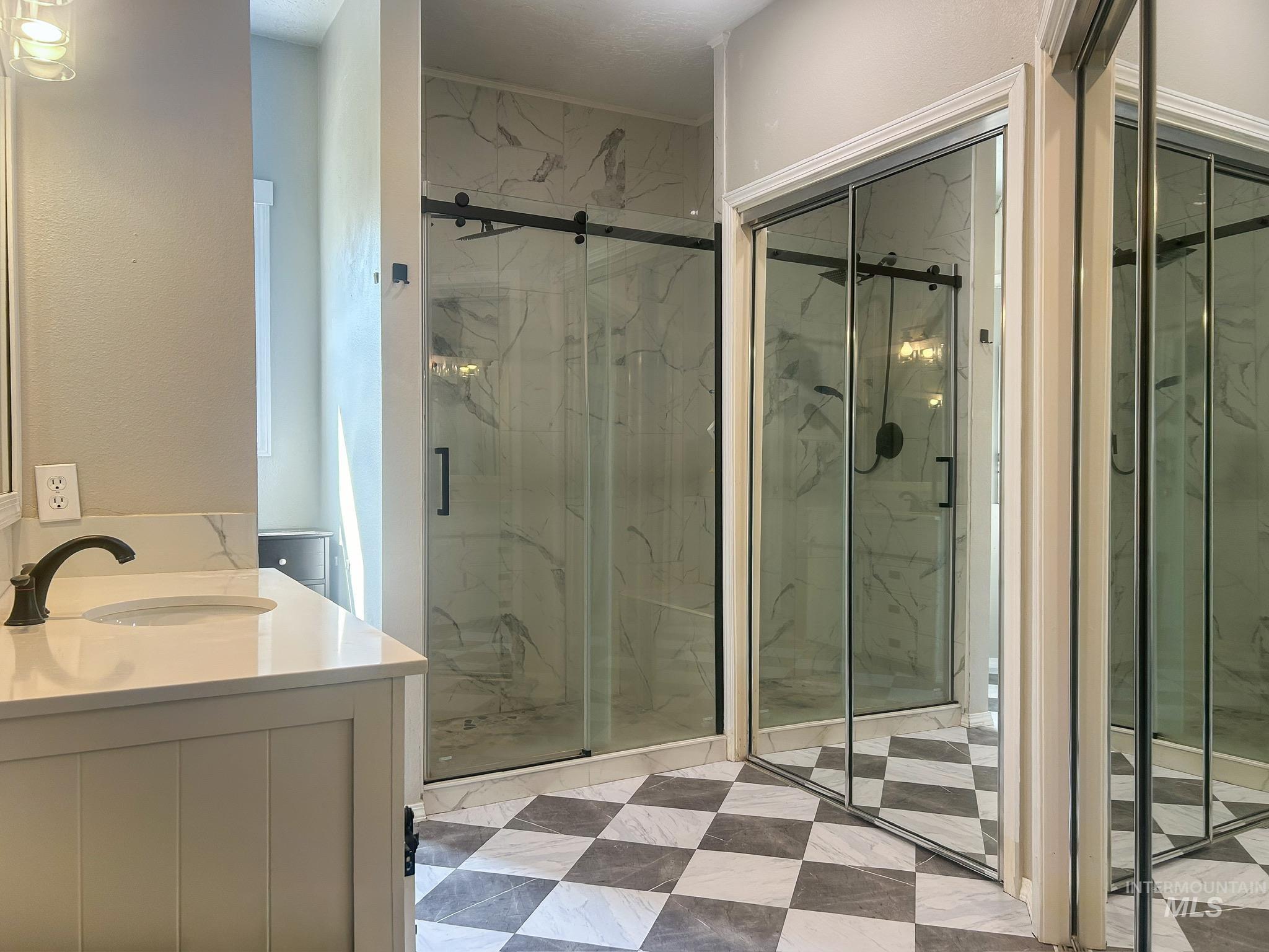Full bath with a marble finish shower and vanity
