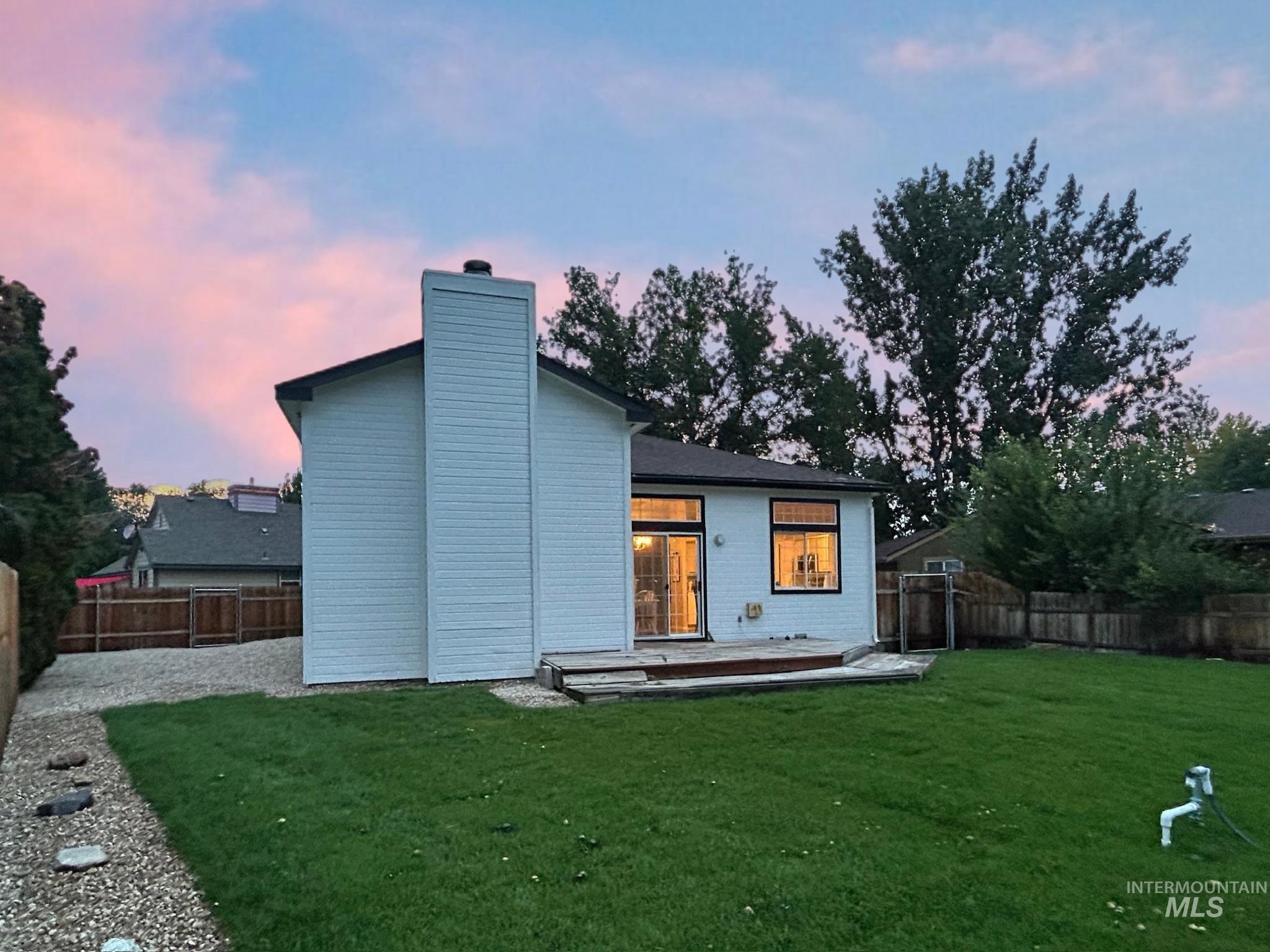 Rear view of house with a deck, a chimney, and a fenced backyard
