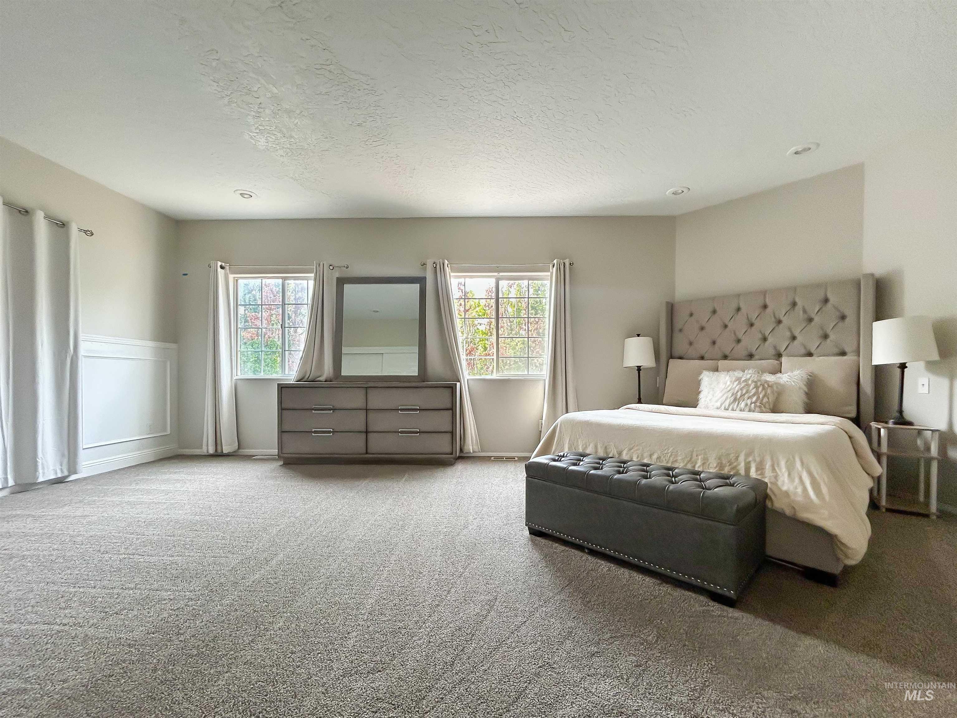 Bedroom with multiple windows, carpet flooring, and a textured ceiling
