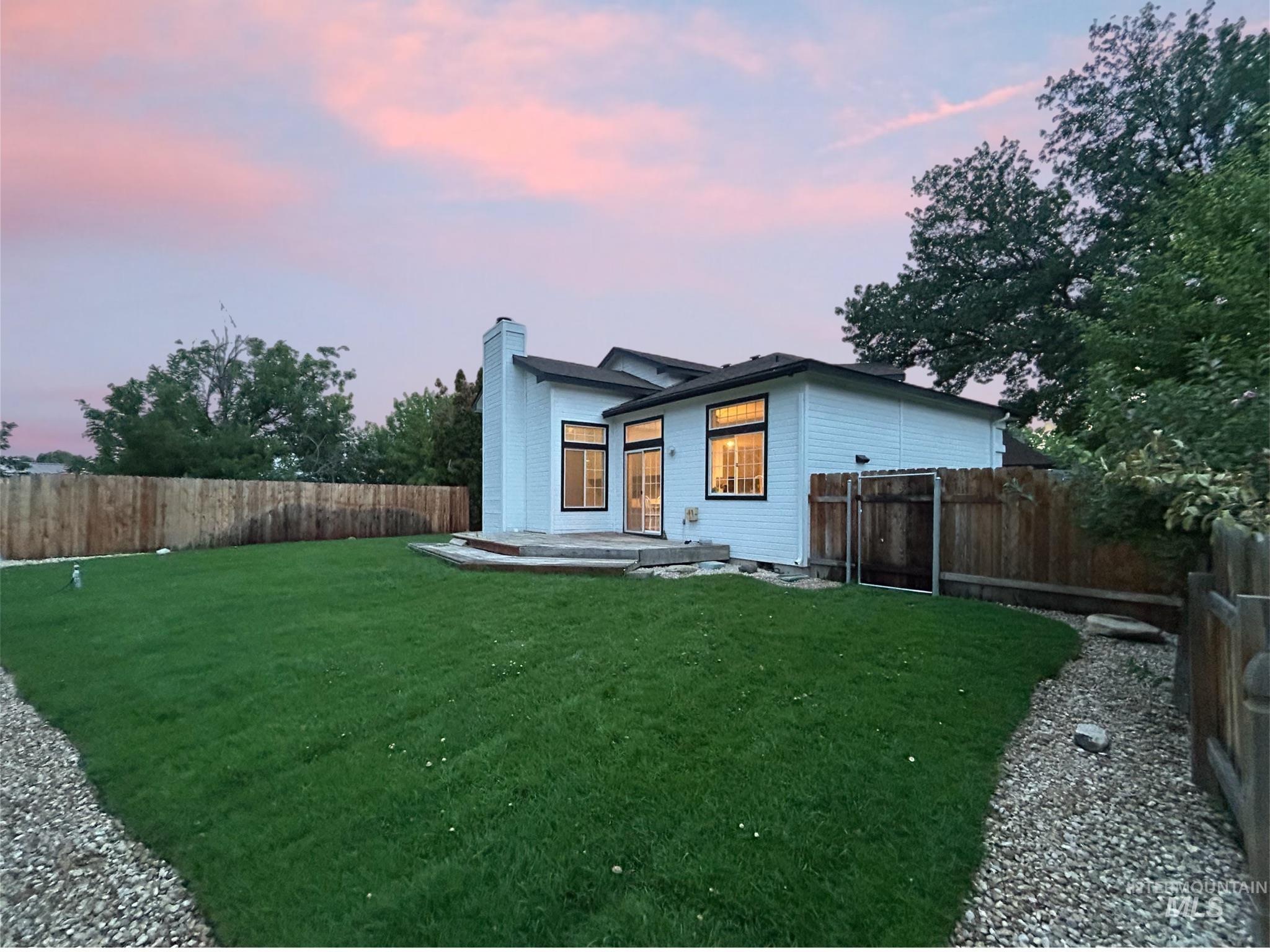 Back of house at dusk featuring a chimney and a fenced backyard