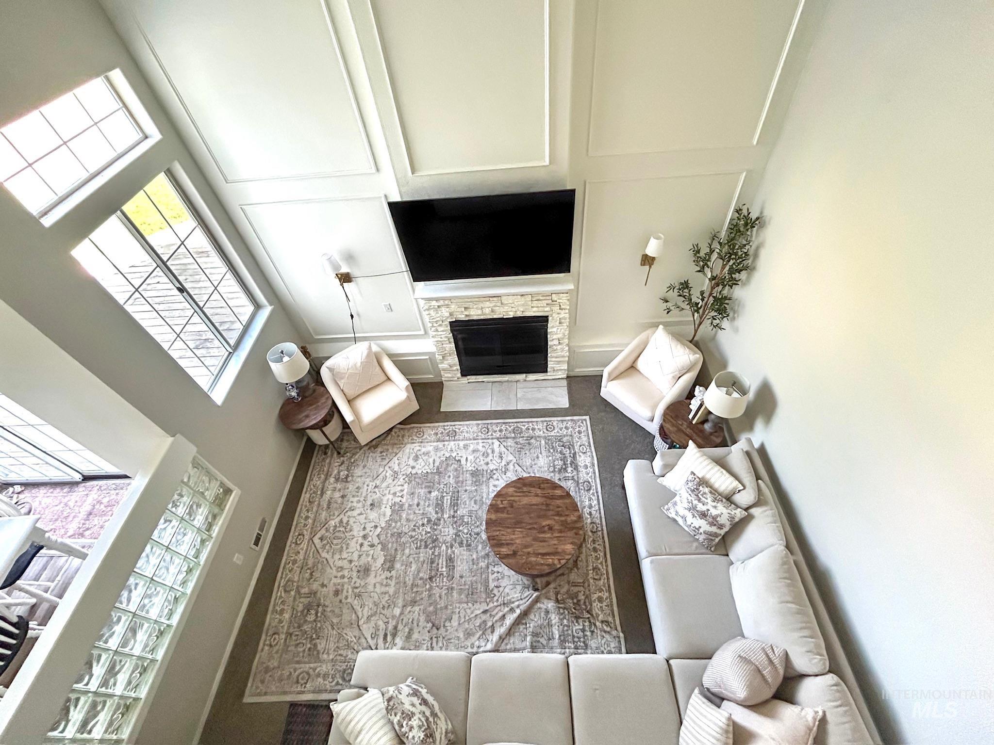 Living area featuring a stone fireplace, a towering ceiling, and a decorative wall