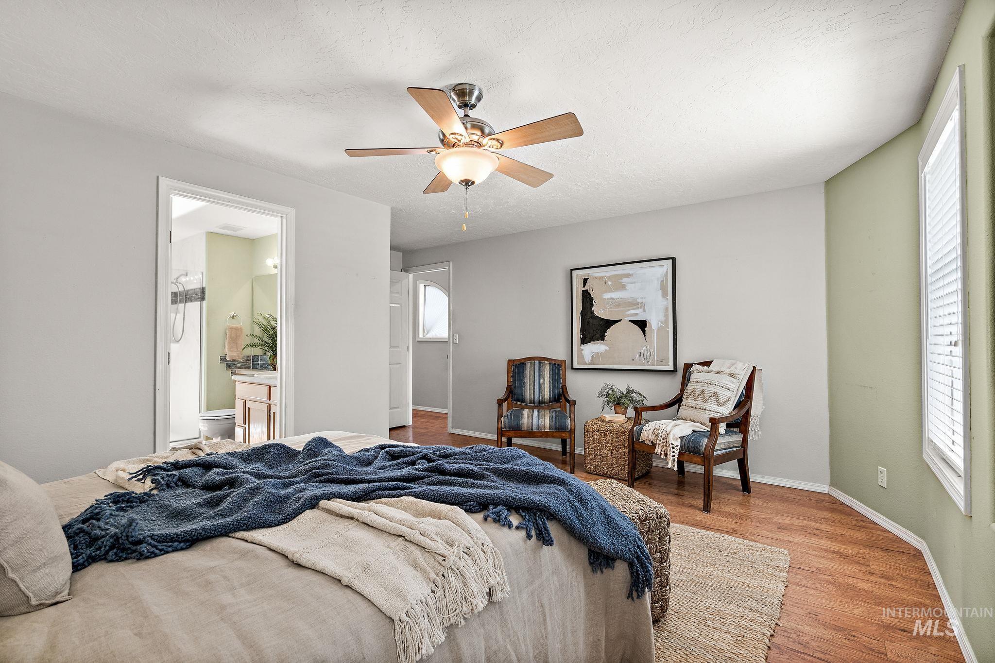 Bedroom with wood finished floors, a ceiling fan, and ensuite bathroom