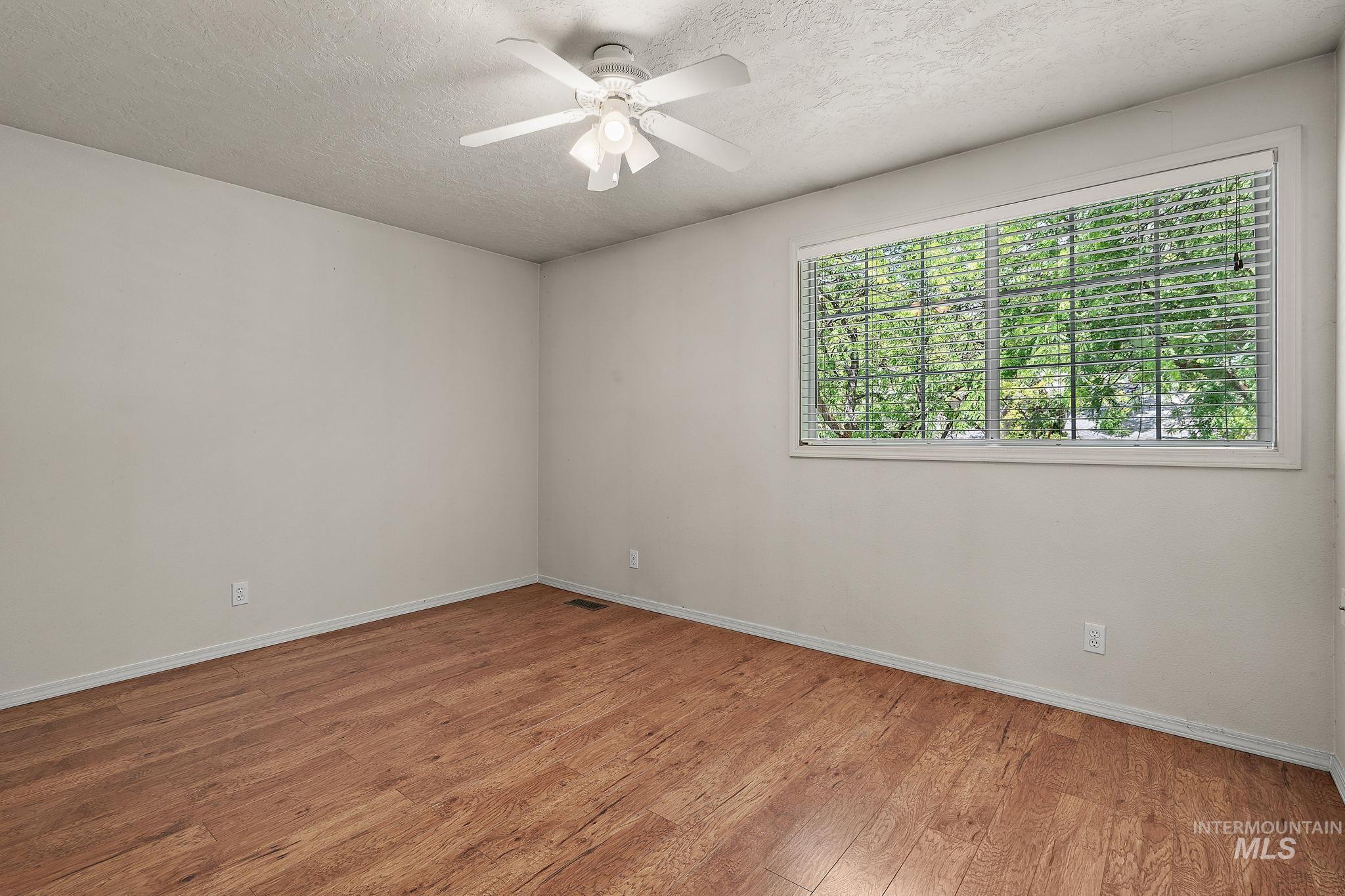 Unfurnished room featuring light wood finished floors, a textured ceiling, and ceiling fan