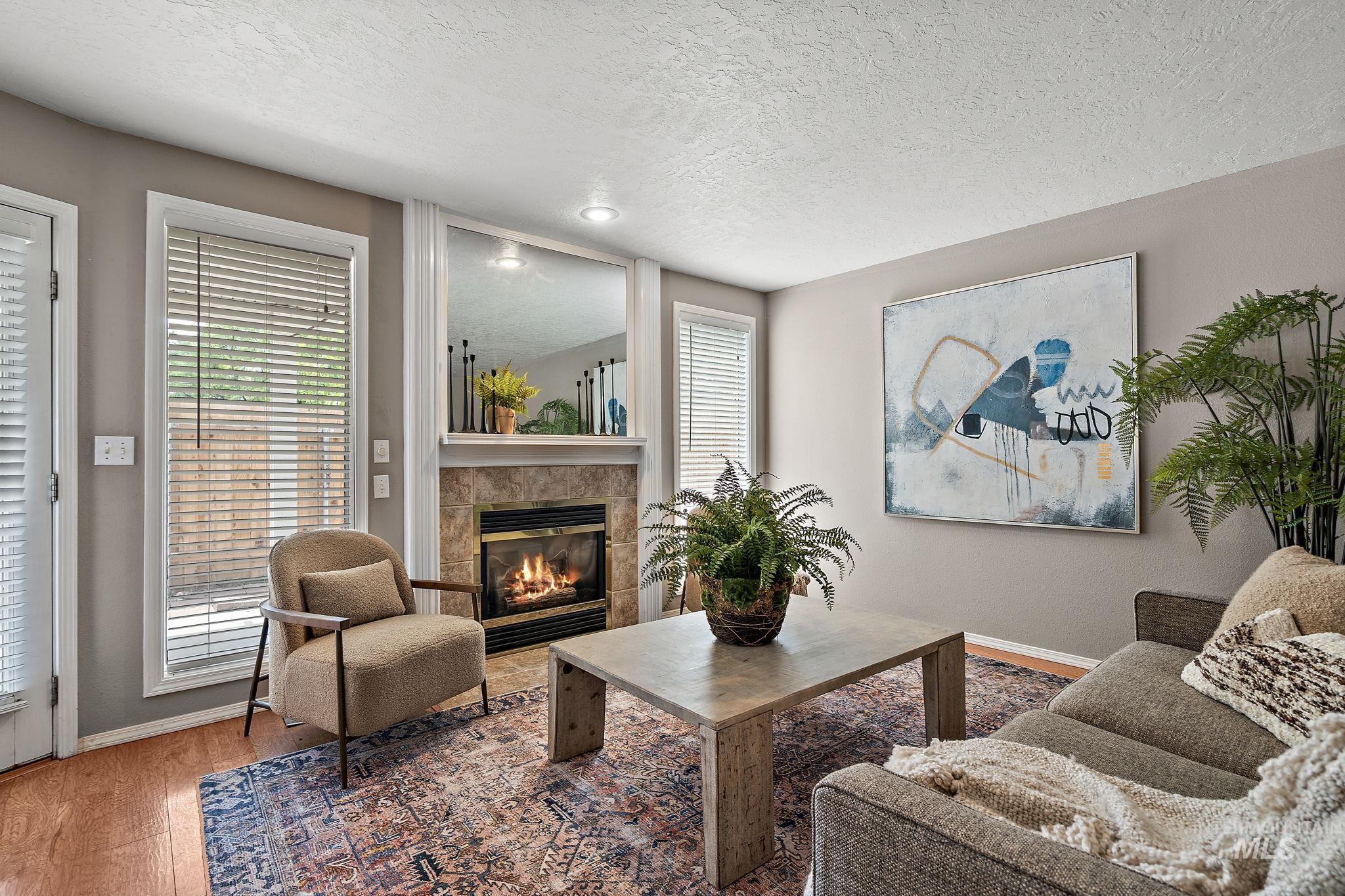 Living room featuring a textured ceiling, a fireplace, wood finished floors, and healthy amount of natural light