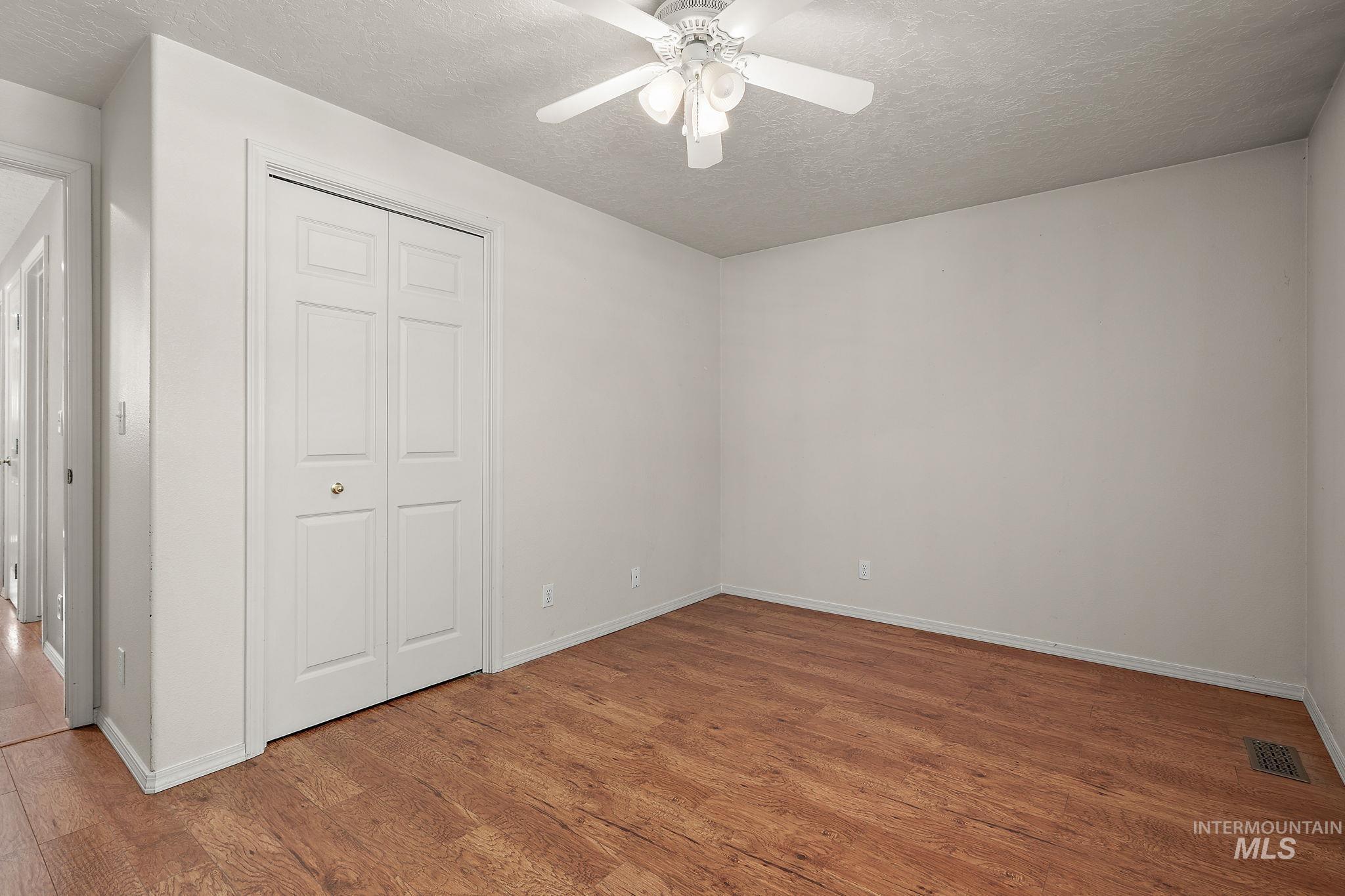 Unfurnished bedroom with light wood finished floors, a textured ceiling, a closet, and a ceiling fan