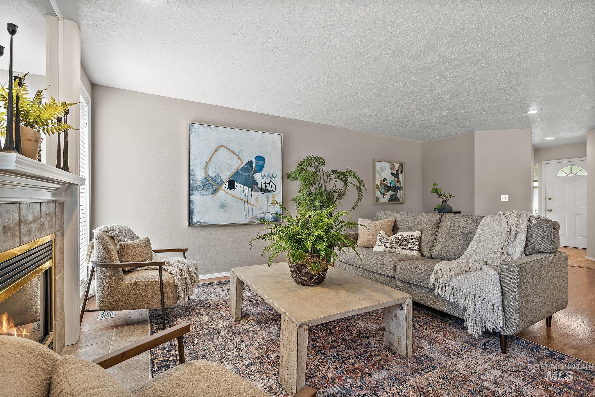 Living area with a tiled fireplace, wood finished floors, a textured ceiling, and recessed lighting