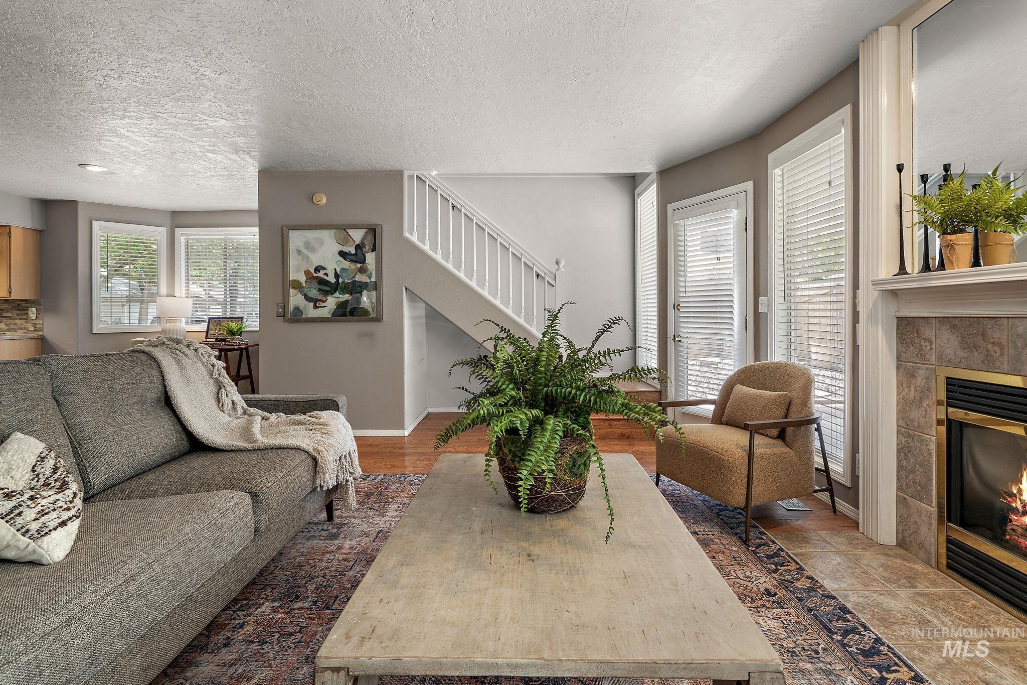 Living area featuring a tile fireplace, stairway, and a textured ceiling