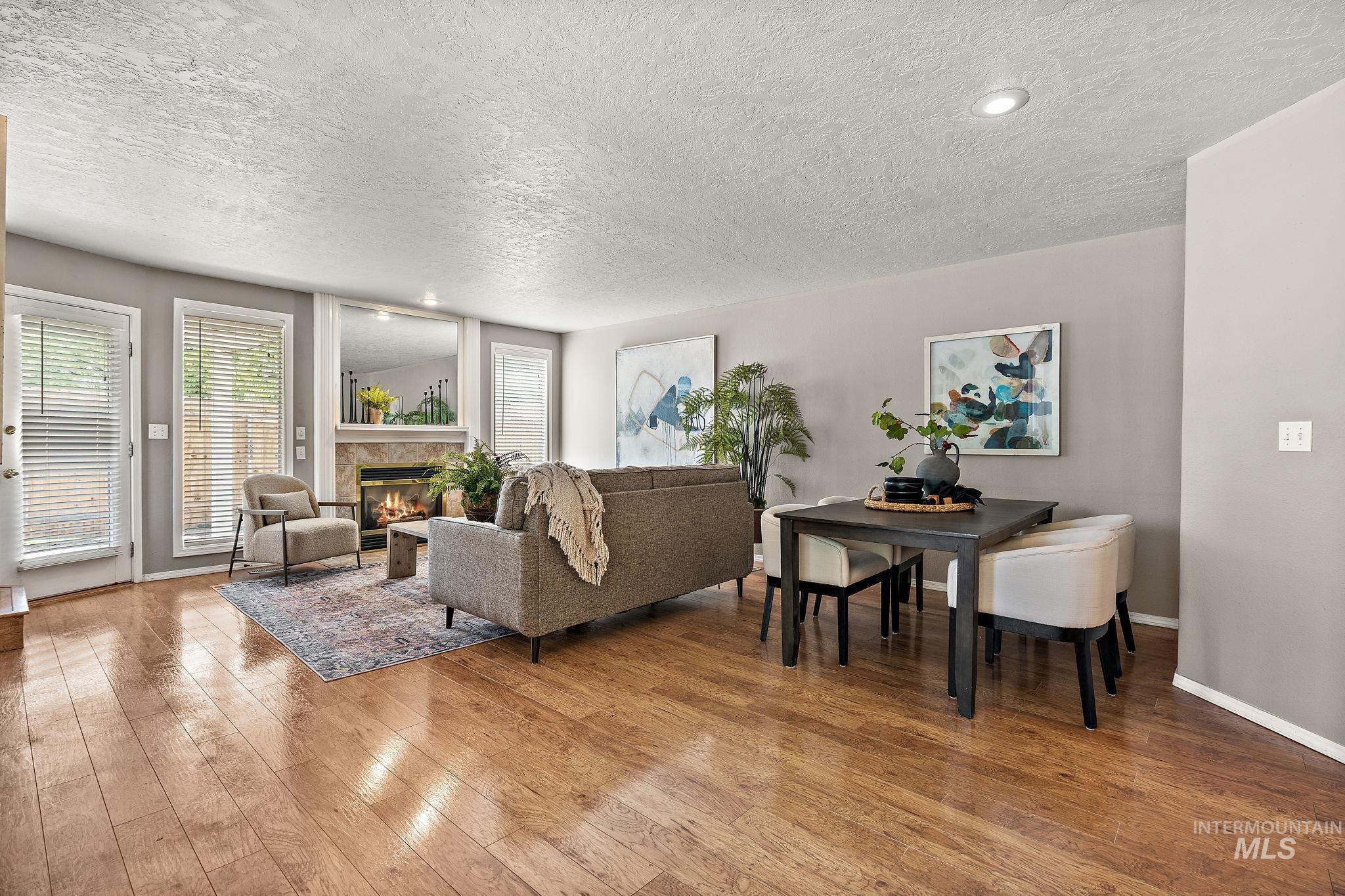 Living area featuring a textured ceiling, wood finished floors, and a glass covered fireplace