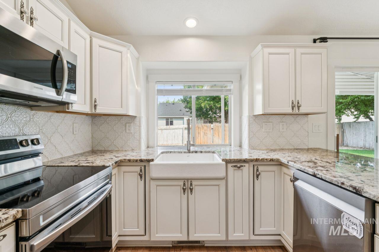 Kitchen featuring appliances with stainless steel finishes, plenty of natural light, backsplash, light stone counters, and recessed lighting