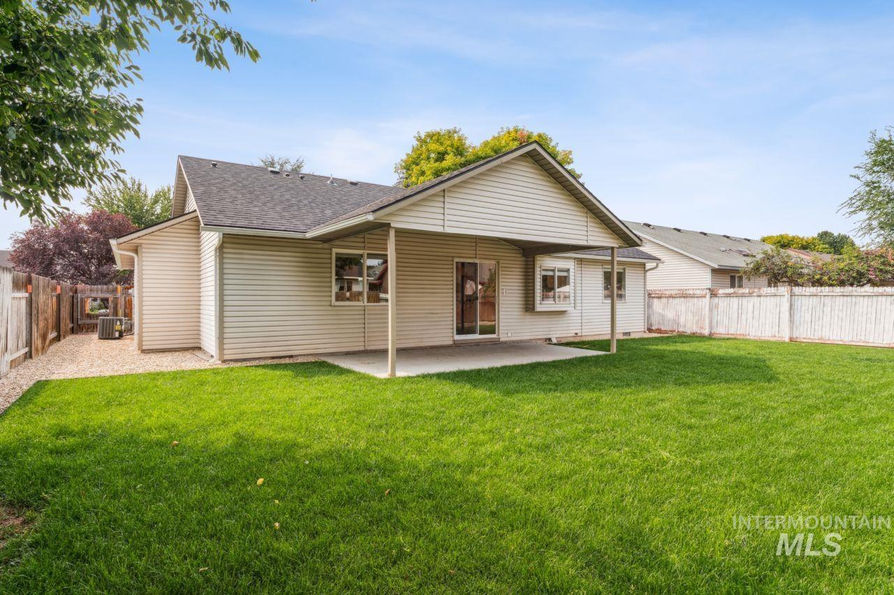 Back of property with a fenced backyard, a patio, and a shingled roof