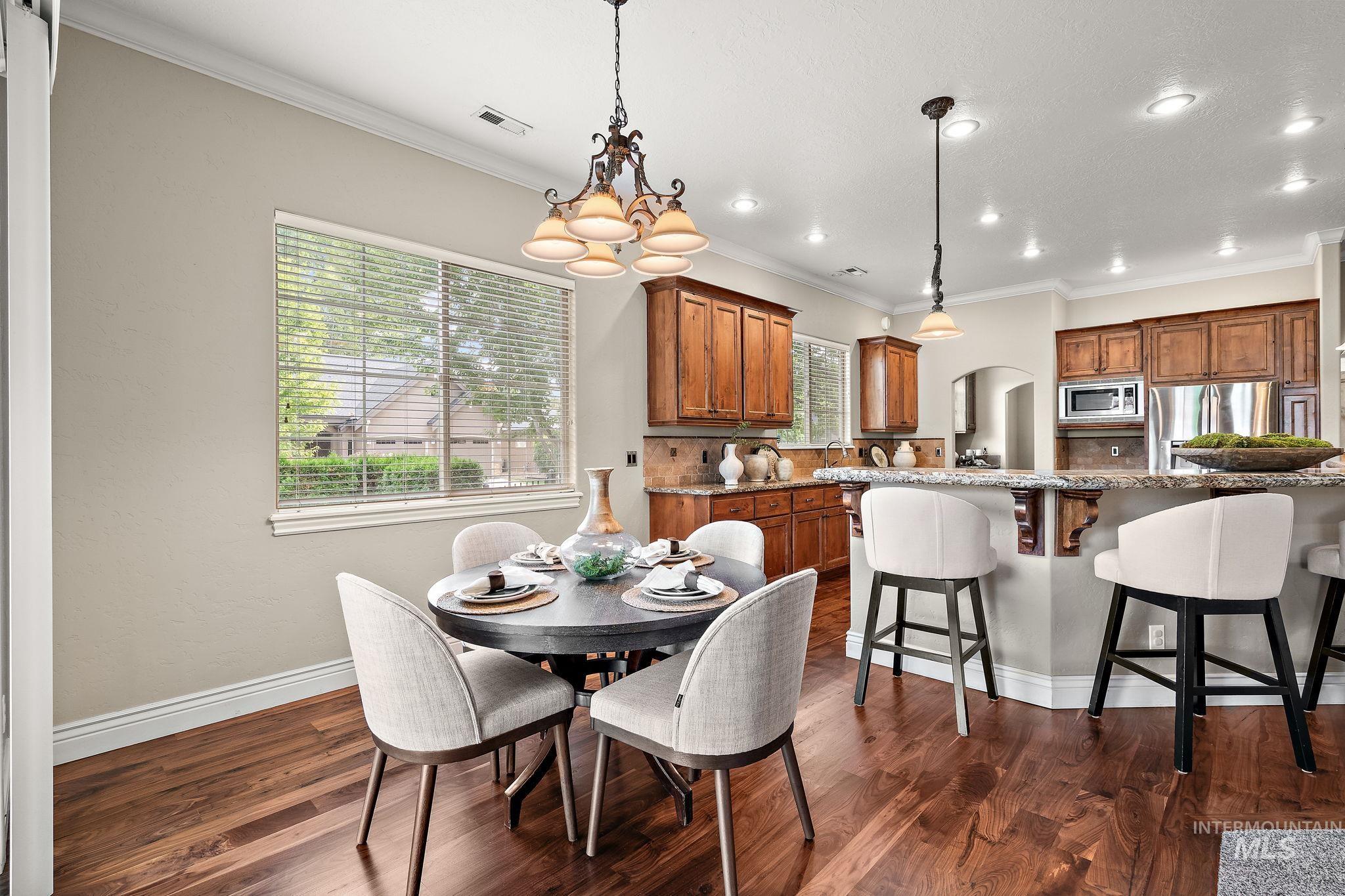 Dining room with ornamental molding, dark wood-style floors, arched walkways, recessed lighting, and a chandelier