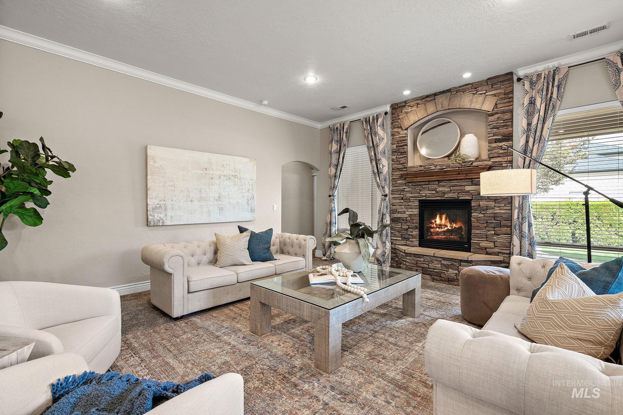 Living area with ornamental molding, arched walkways, a textured ceiling, a fireplace, and recessed lighting