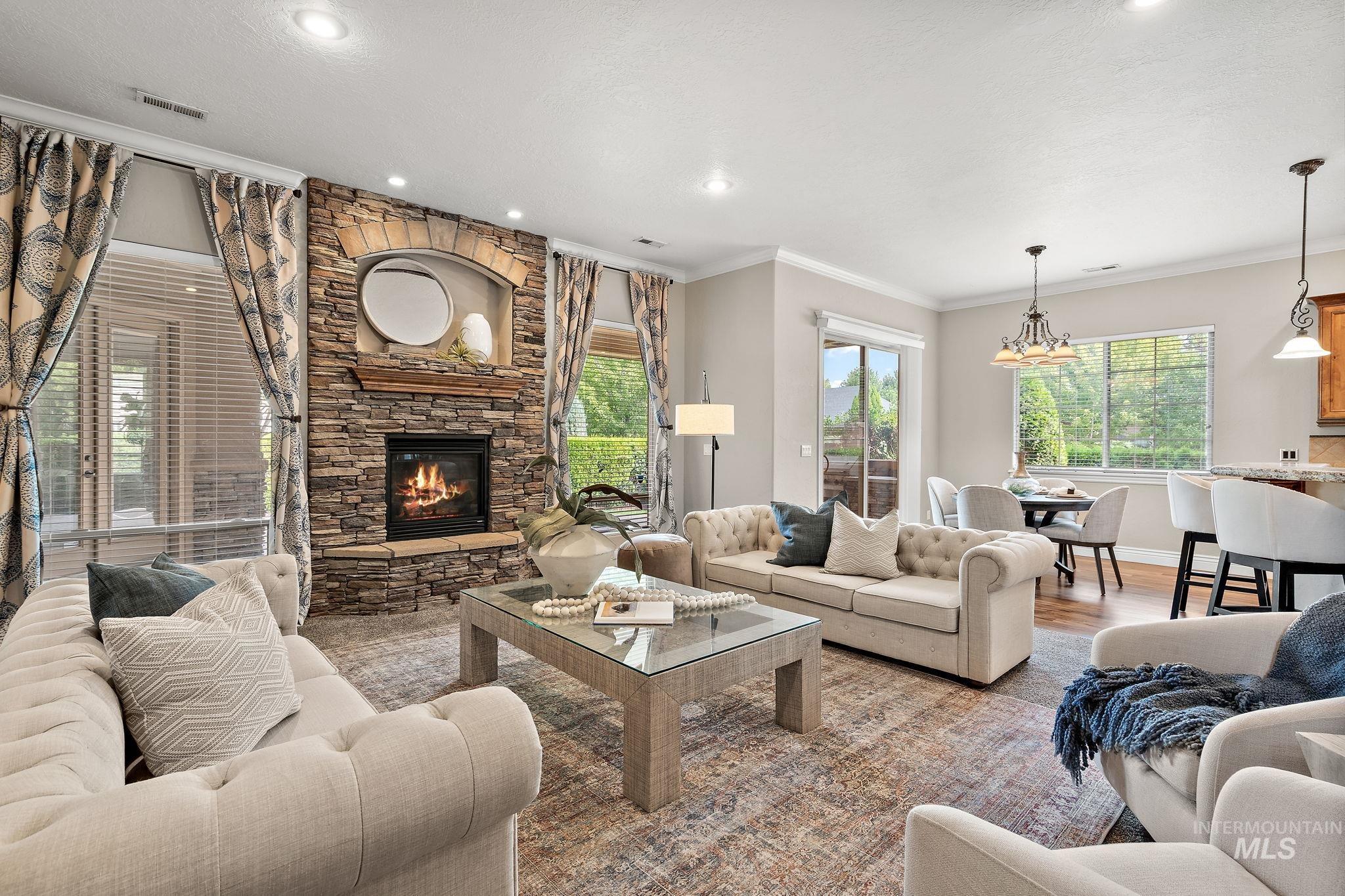 Living room featuring crown molding, a stone fireplace, wood finished floors, and recessed lighting