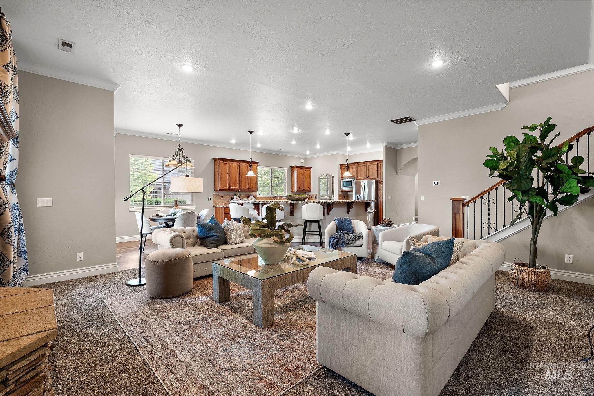 Living area with dark carpet, crown molding, stairway, a textured ceiling, and recessed lighting
