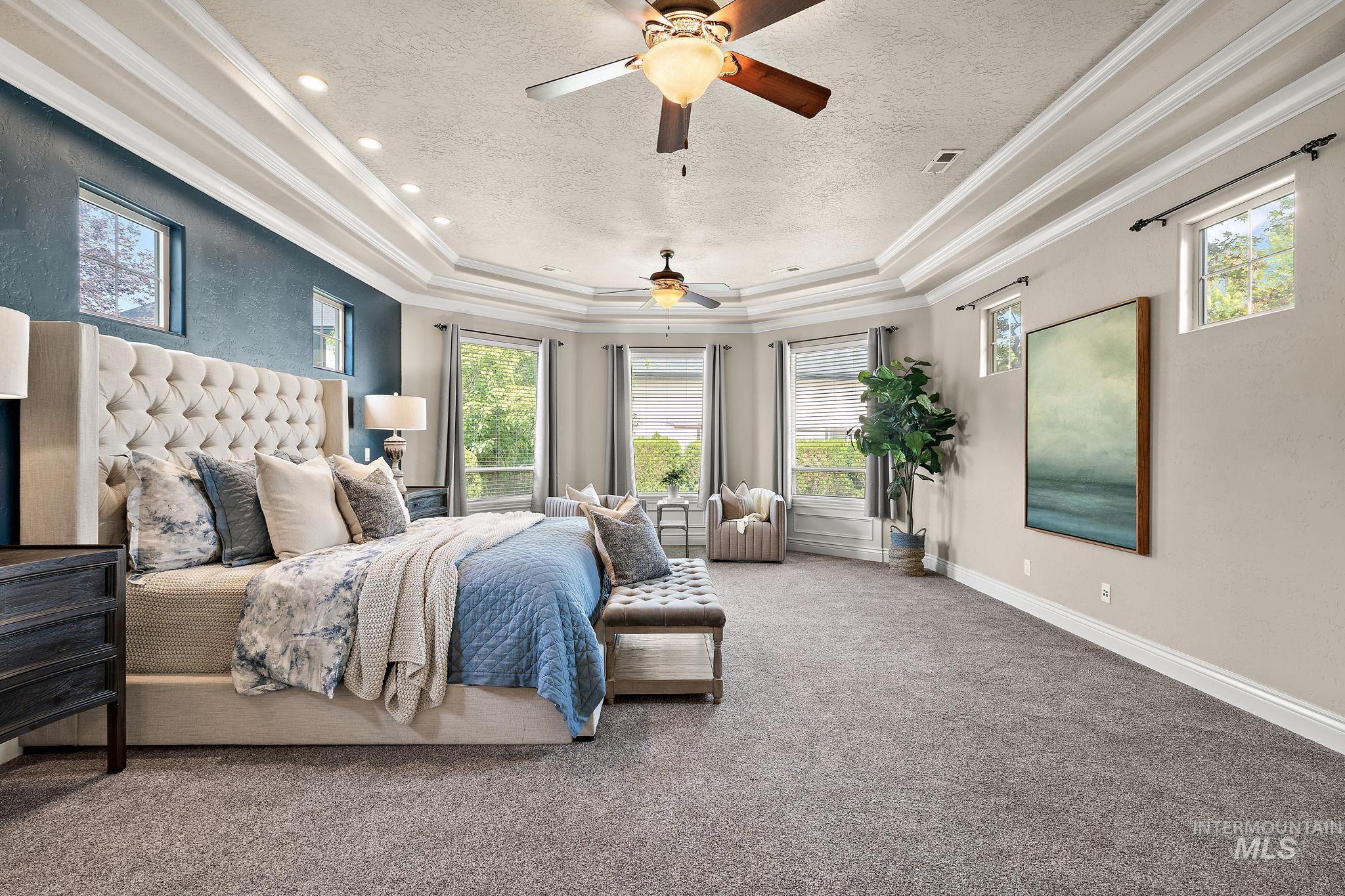 Bedroom featuring carpet flooring, crown molding, a textured ceiling, a raised ceiling, and ceiling fan