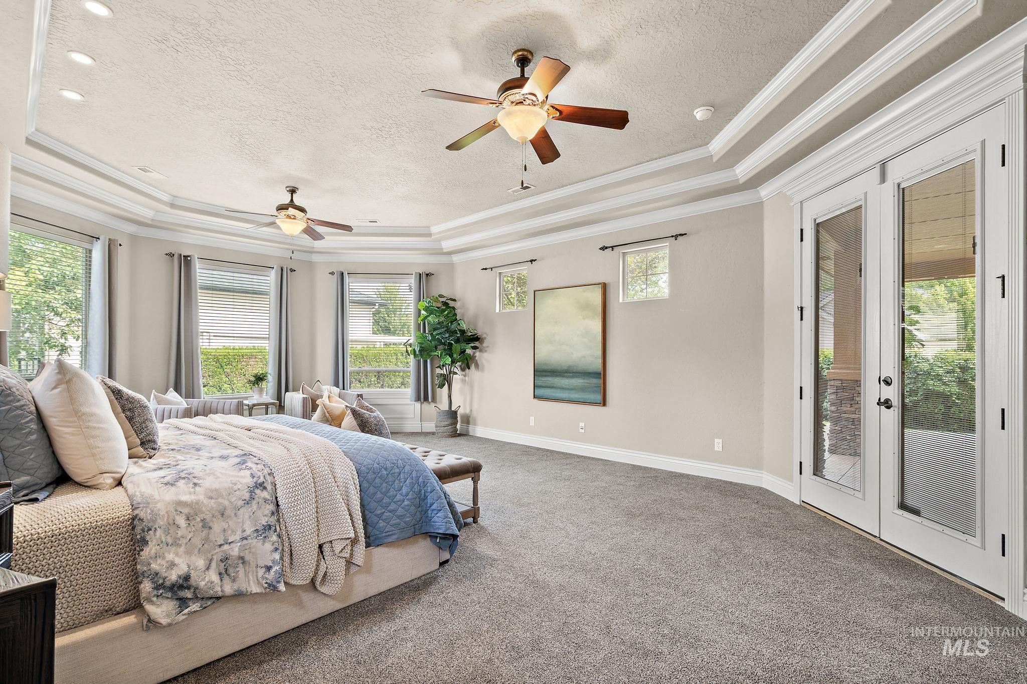 Bedroom with access to outside, carpet flooring, crown molding, a textured ceiling, and a tray ceiling