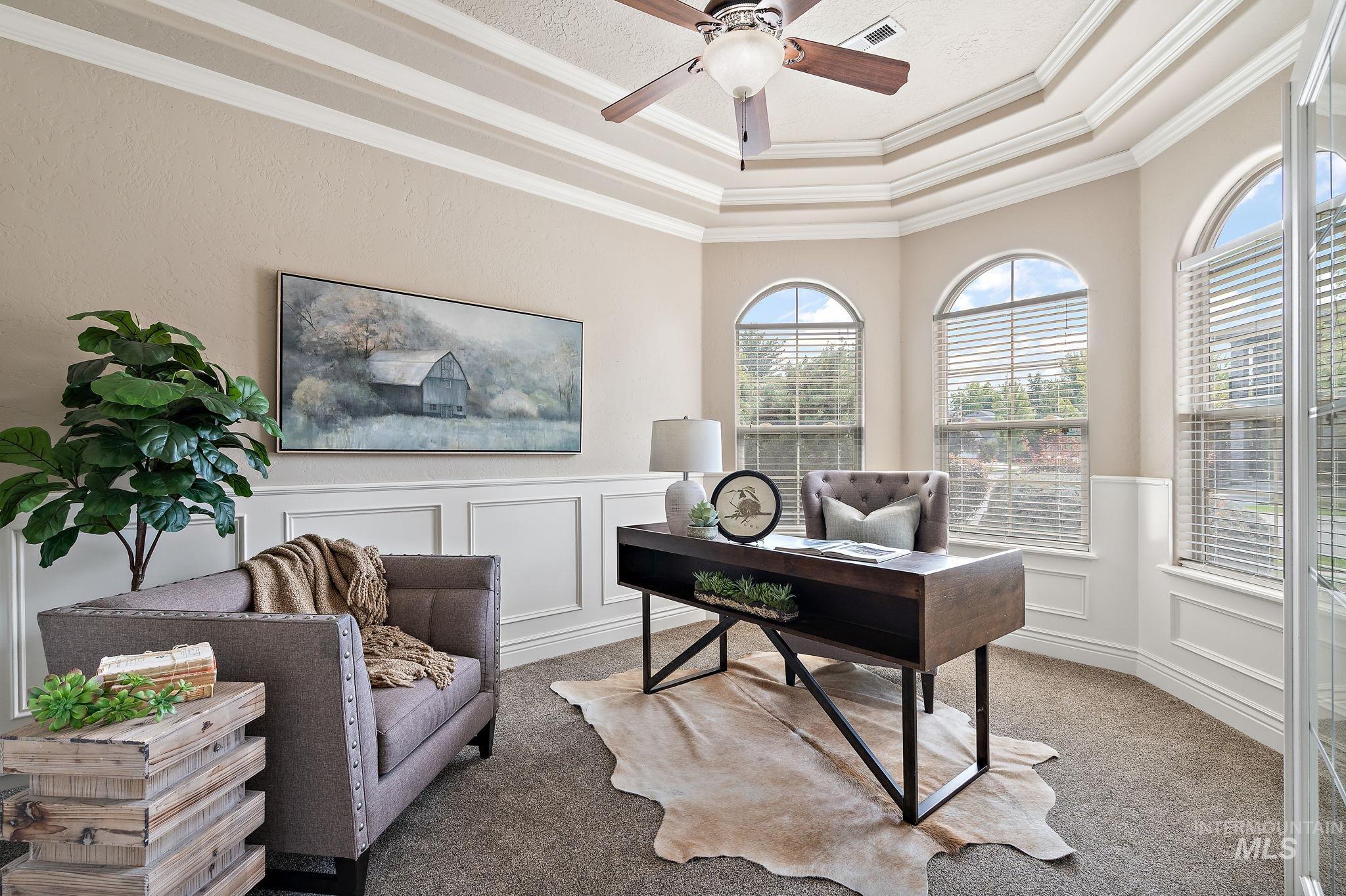 Office area with crown molding, a raised ceiling, carpet floors, a decorative wall, and a wainscoted wall