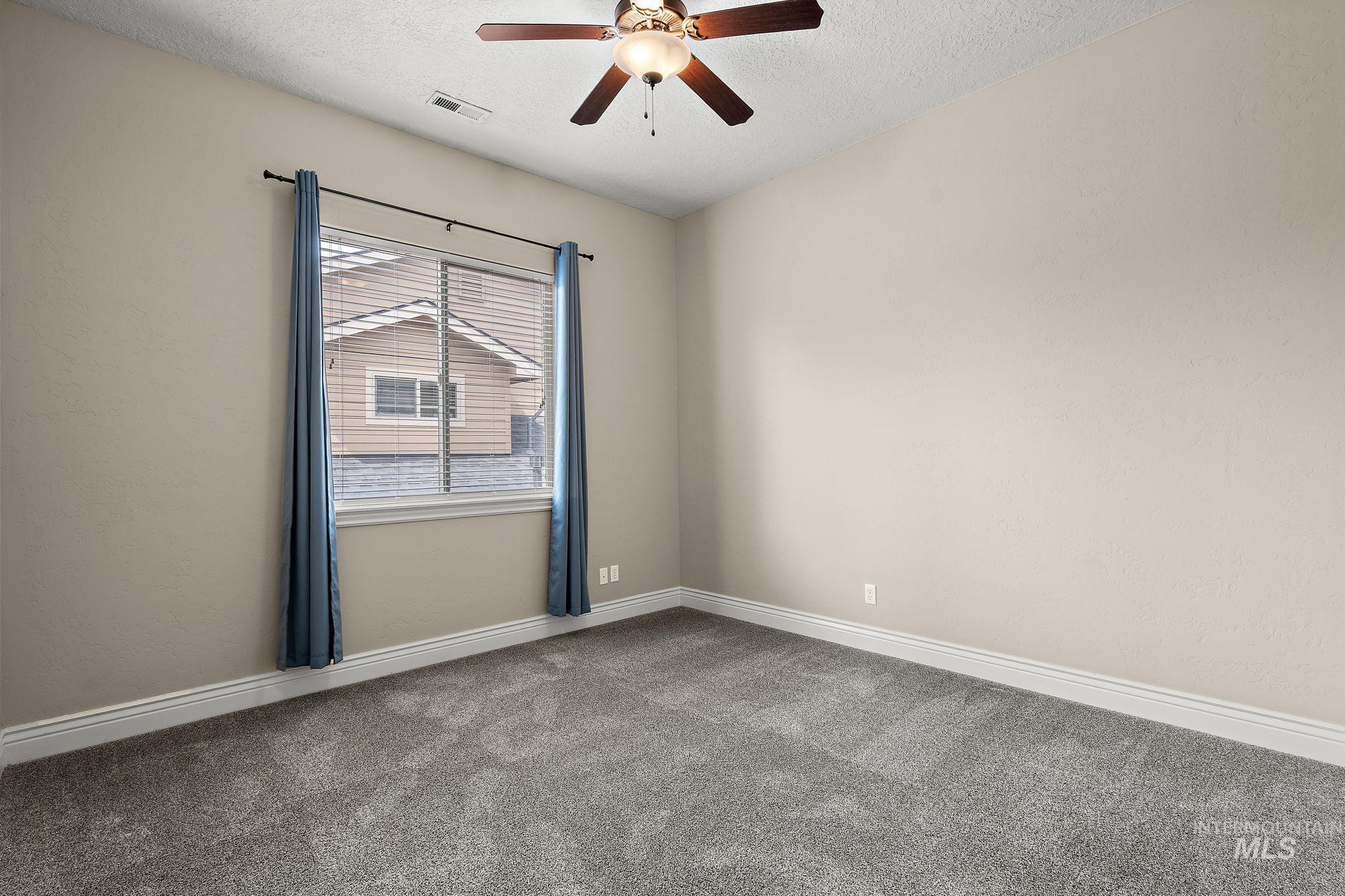 Spare room with carpet, a textured ceiling, and ceiling fan