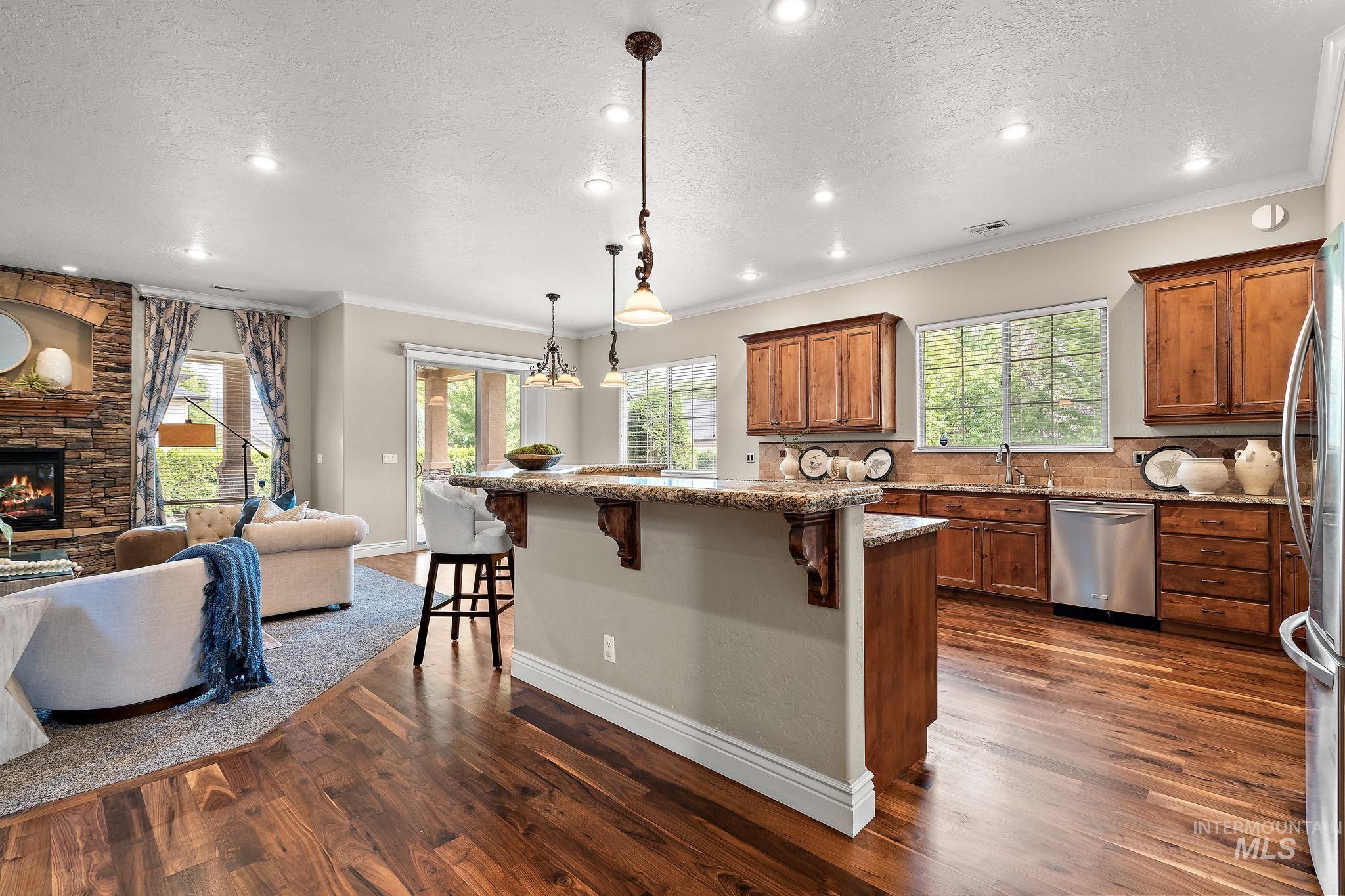 Kitchen featuring ornamental molding, a breakfast bar, open floor plan, pendant lighting, and decorative backsplash