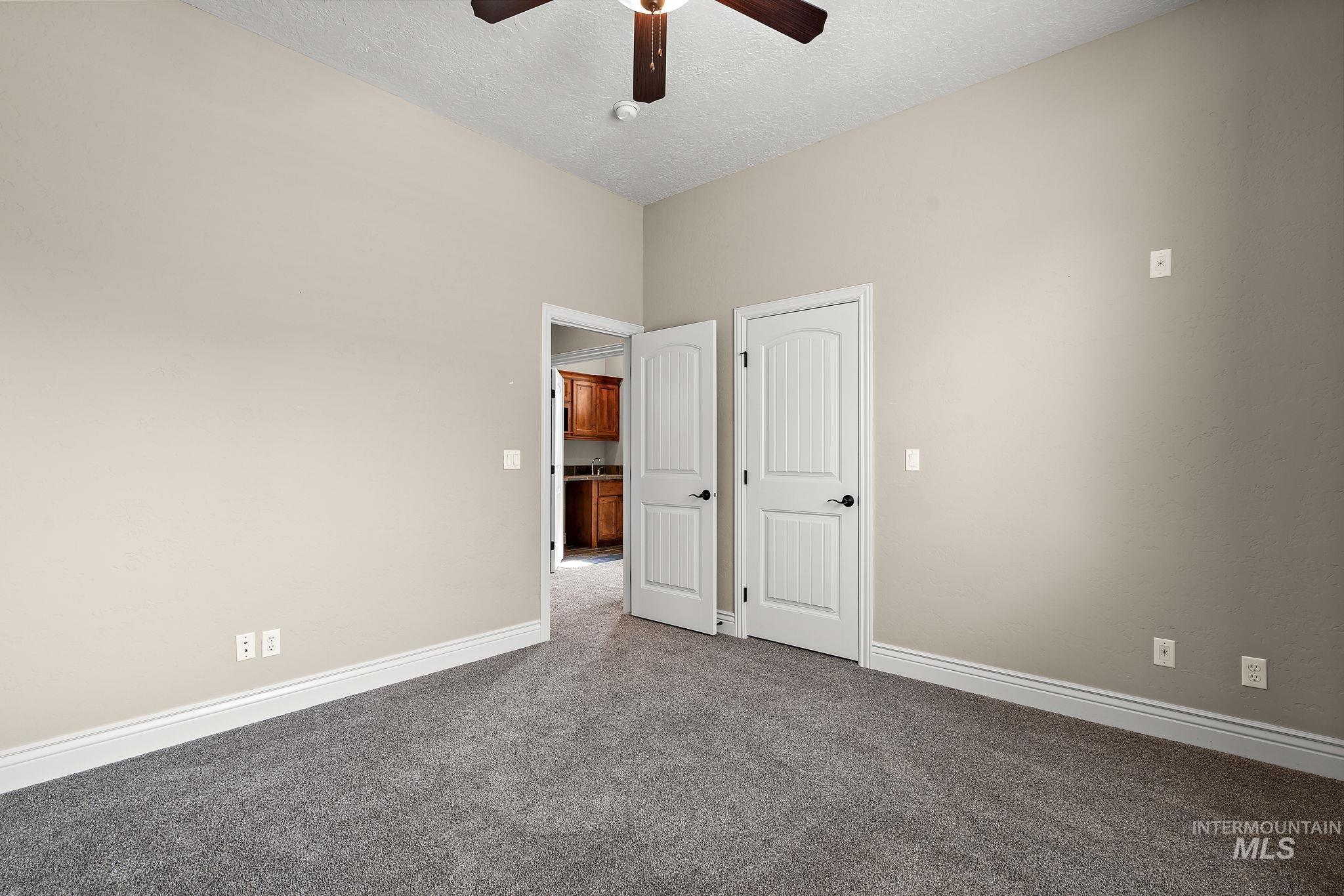 Unfurnished room featuring carpet flooring, ceiling fan, and a textured ceiling