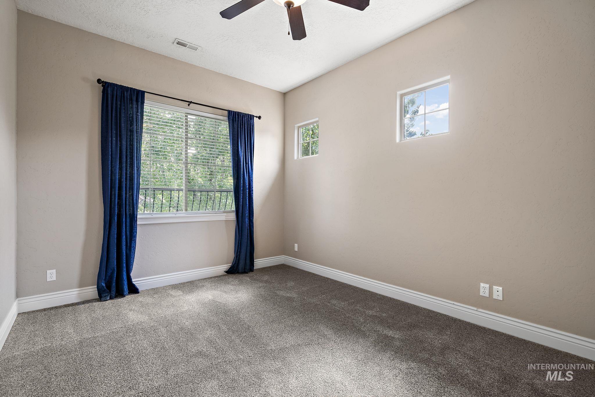 Carpeted empty room with ceiling fan and a textured ceiling