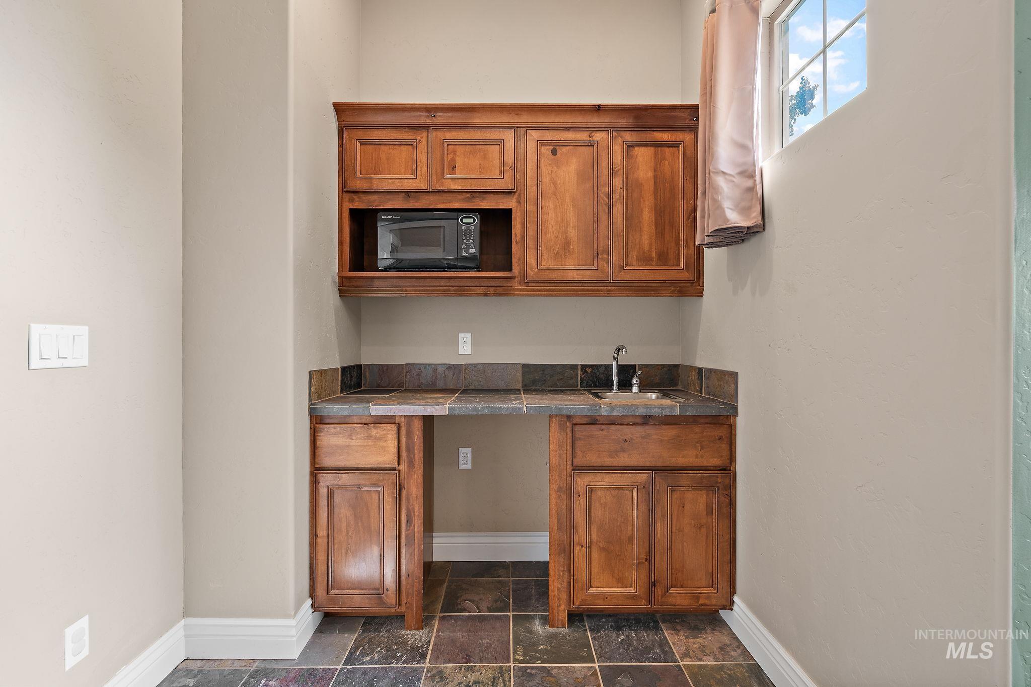 Kitchen featuring brown cabinetry and black microwave
