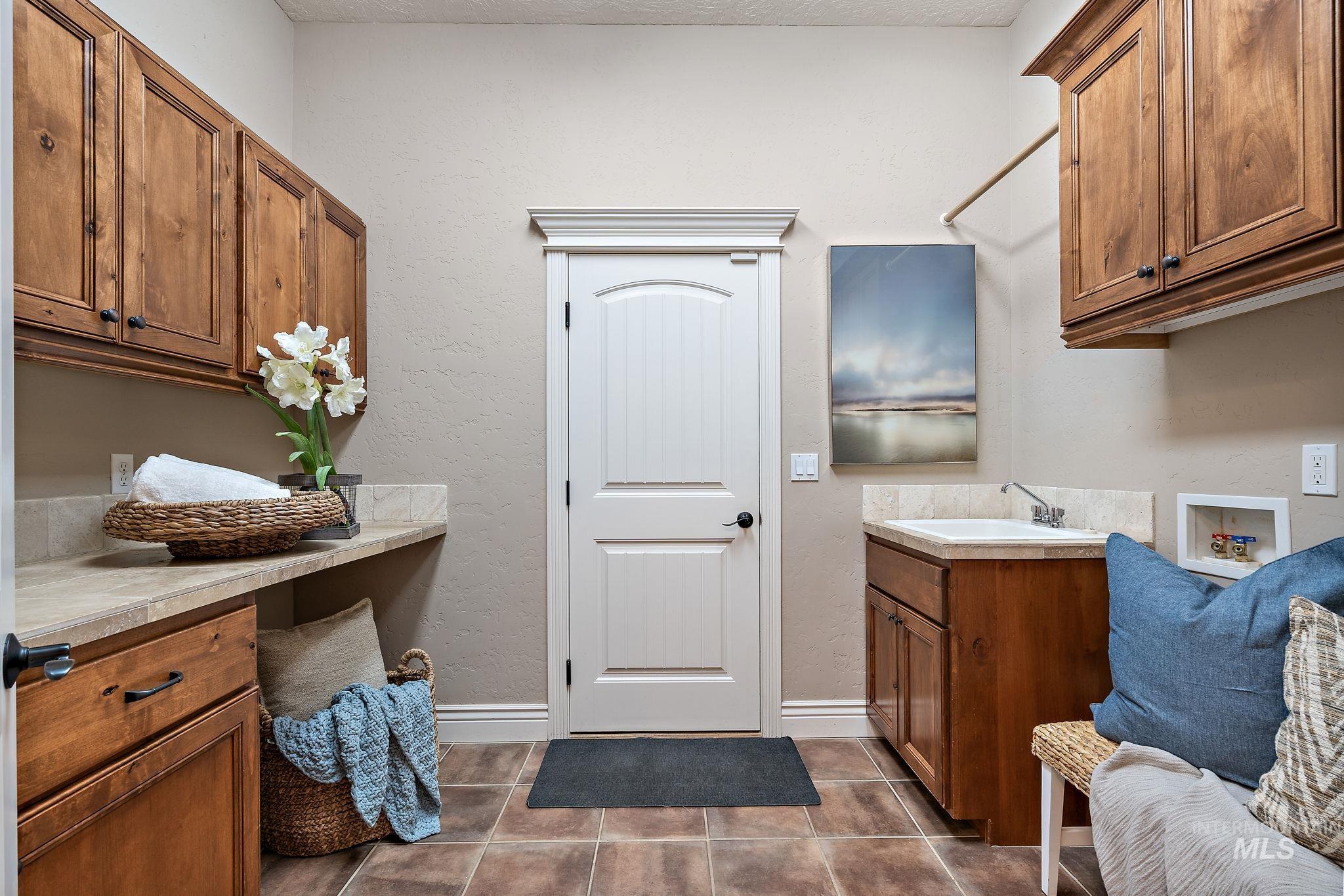 Laundry room featuring dark tile patterned floors, hookup for a washing machine, and cabinet space