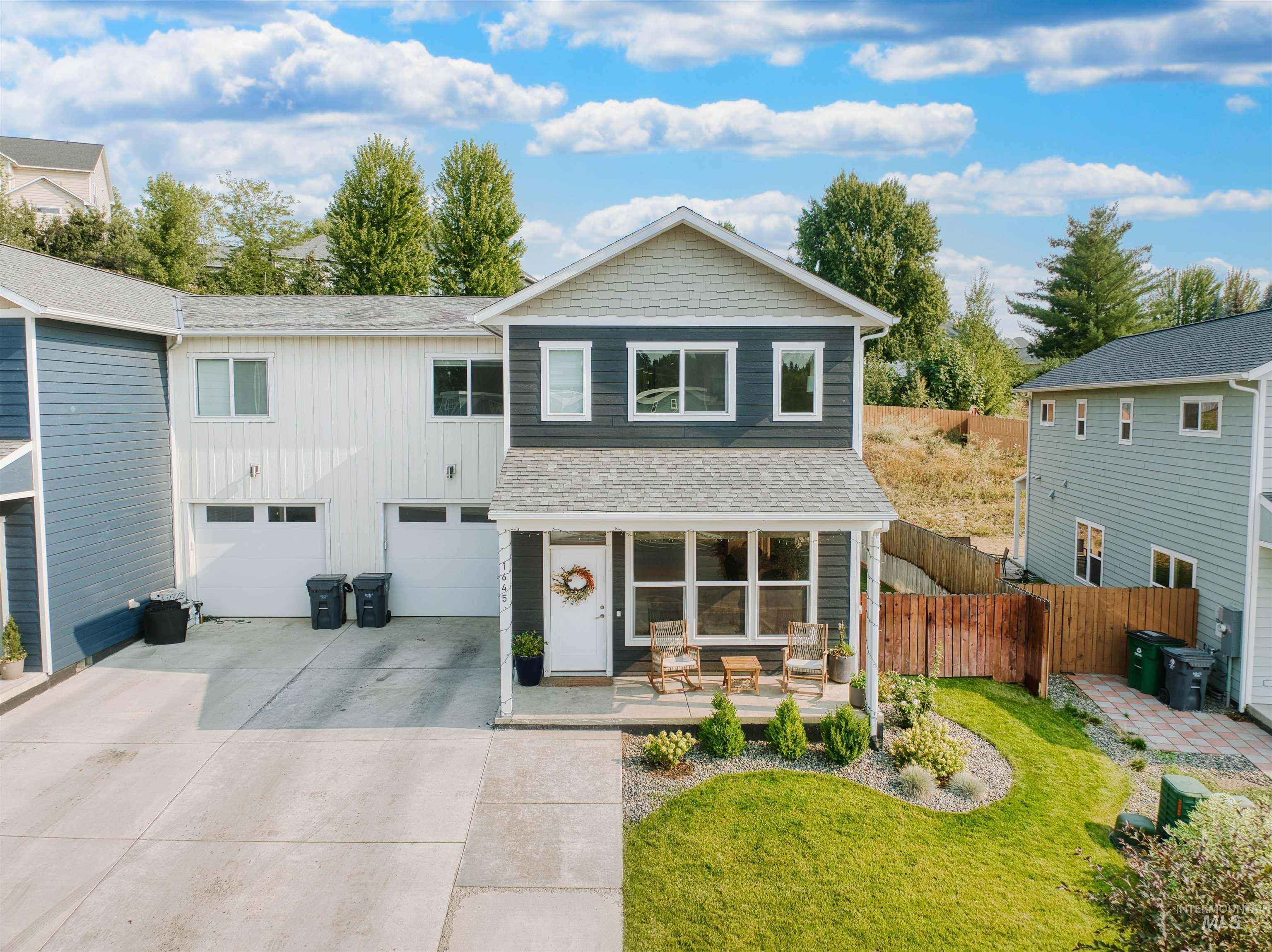 View of front of property featuring driveway, a shingled roof, an attached garage, and board and batten siding