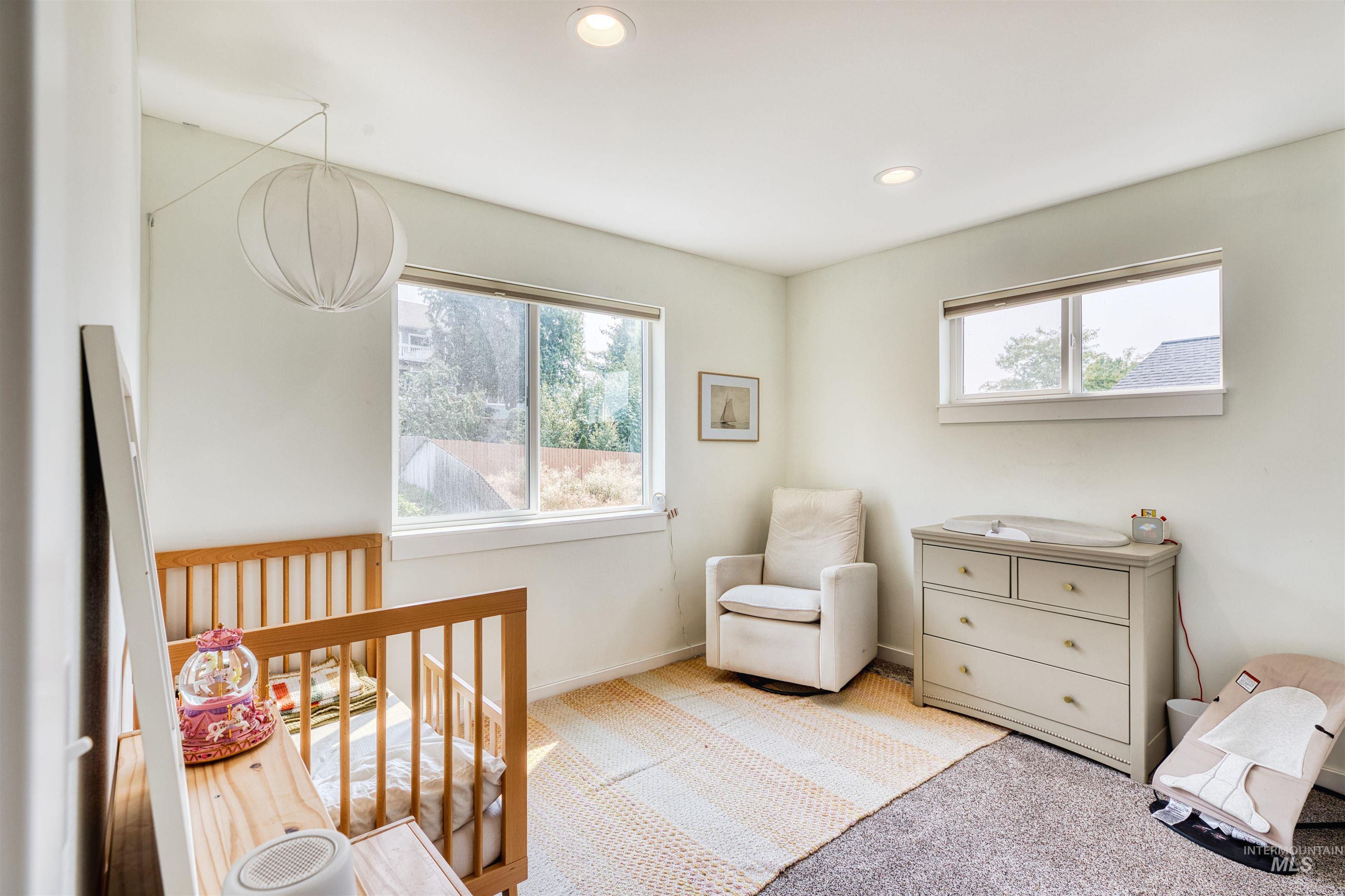 Carpeted bedroom featuring a nursery area, multiple windows, and recessed lighting