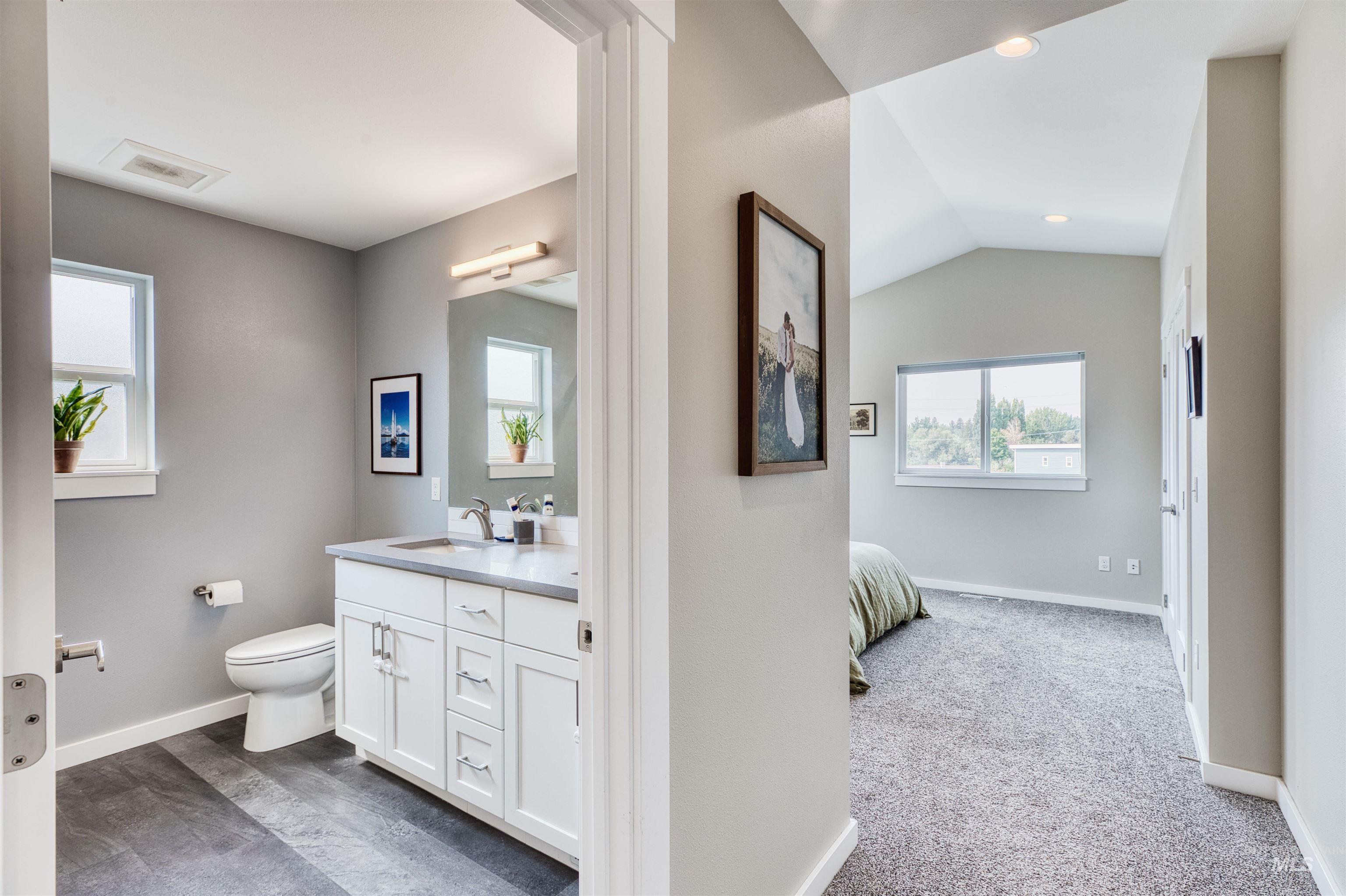 Full bathroom featuring plenty of natural light, double vanity, lofted ceiling, connected bathroom, and recessed lighting