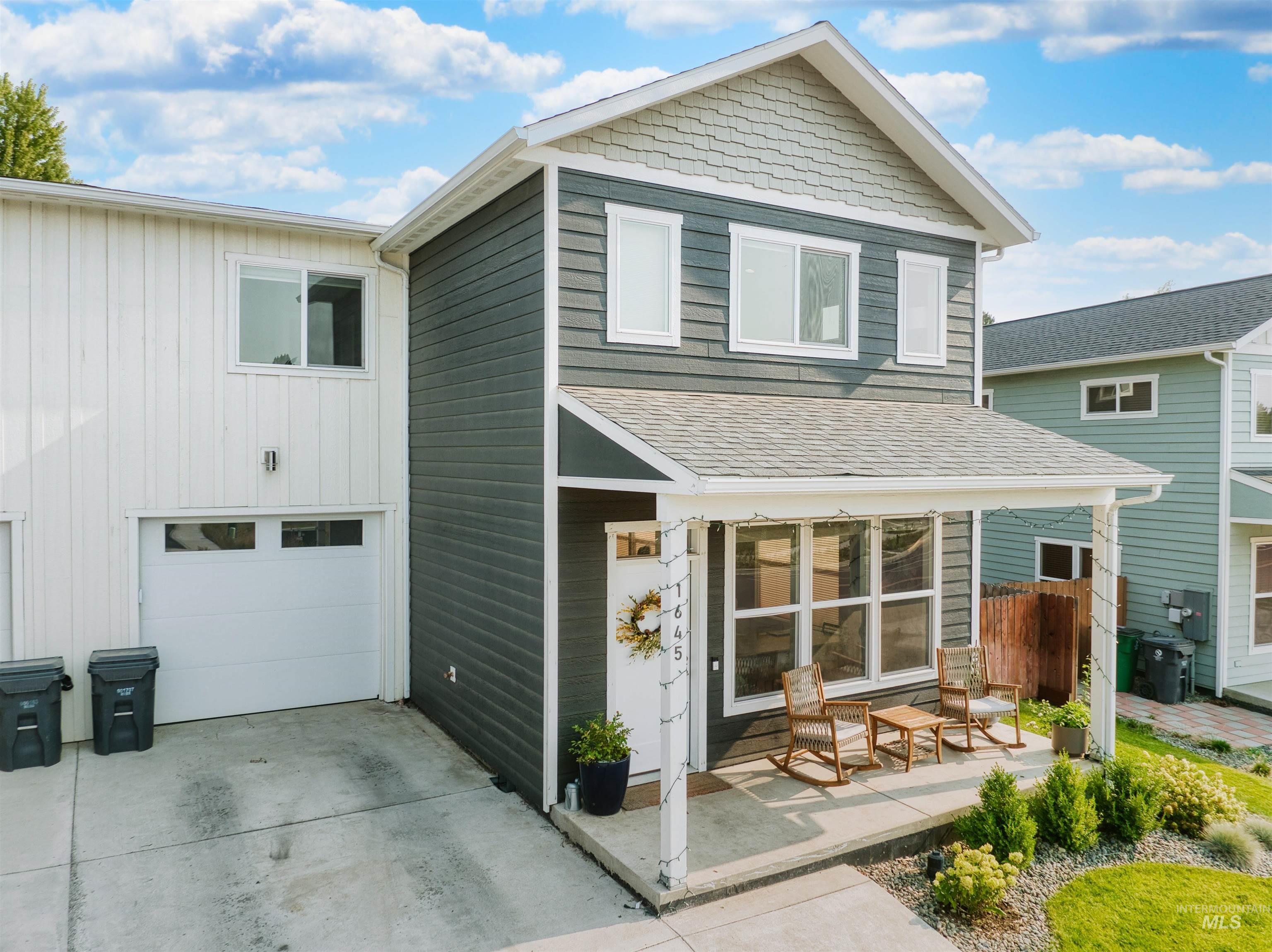 View of front of house with board and batten siding, concrete driveway, and roof with shingles
