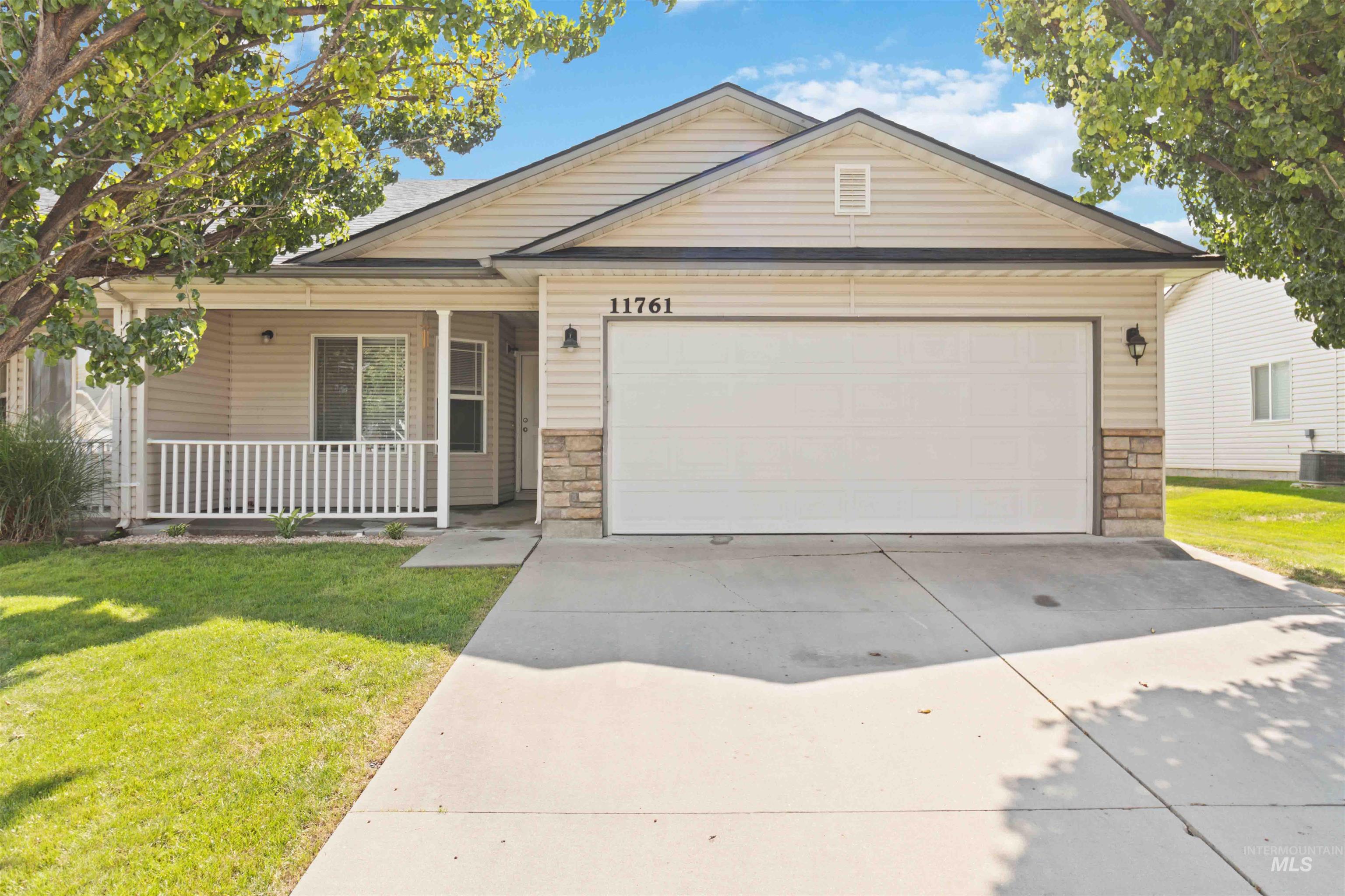 Ranch-style home with stone siding, covered porch, driveway, and an attached garage