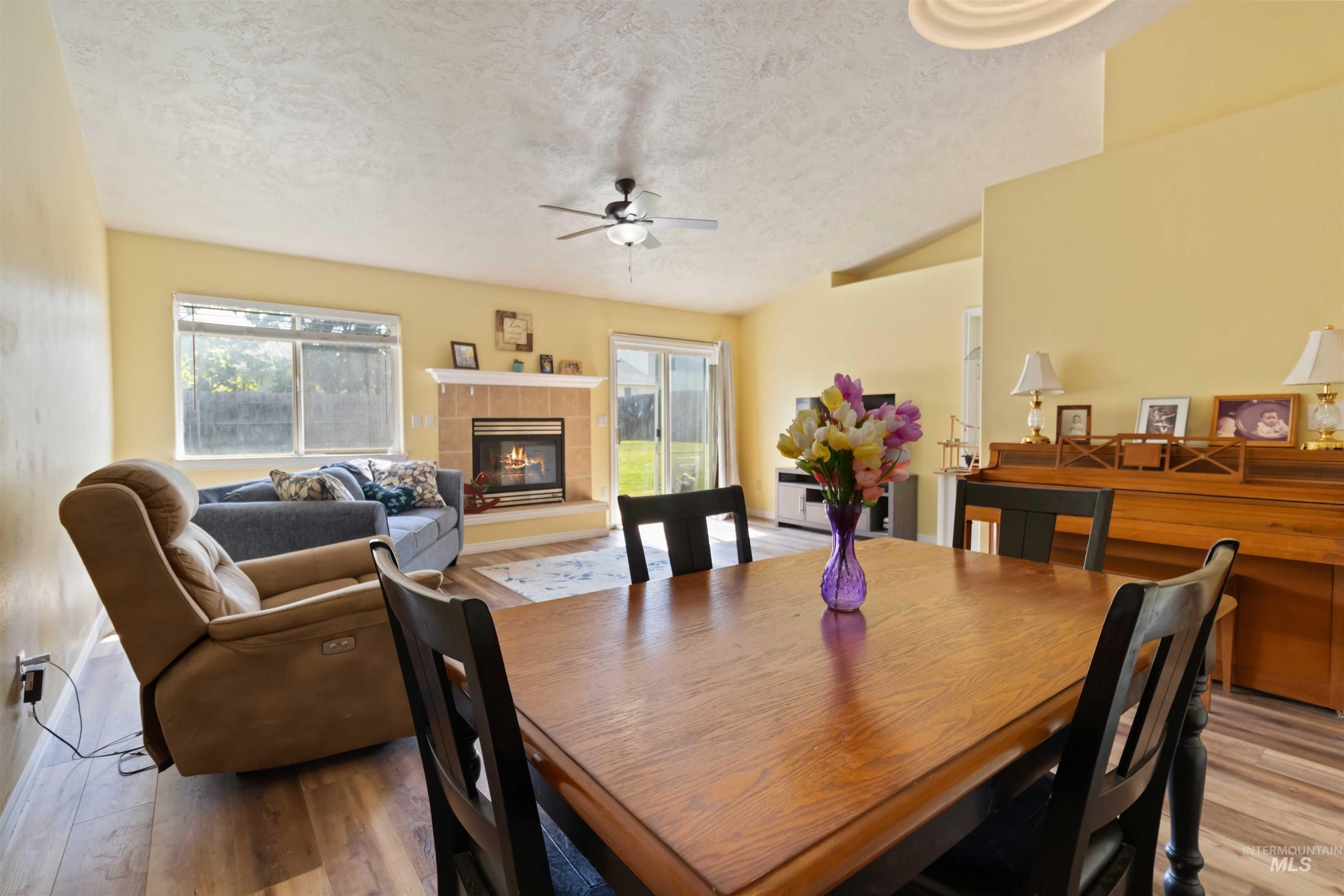 Dining area with plenty of natural light, a tile fireplace, a textured ceiling, and light wood finished floors