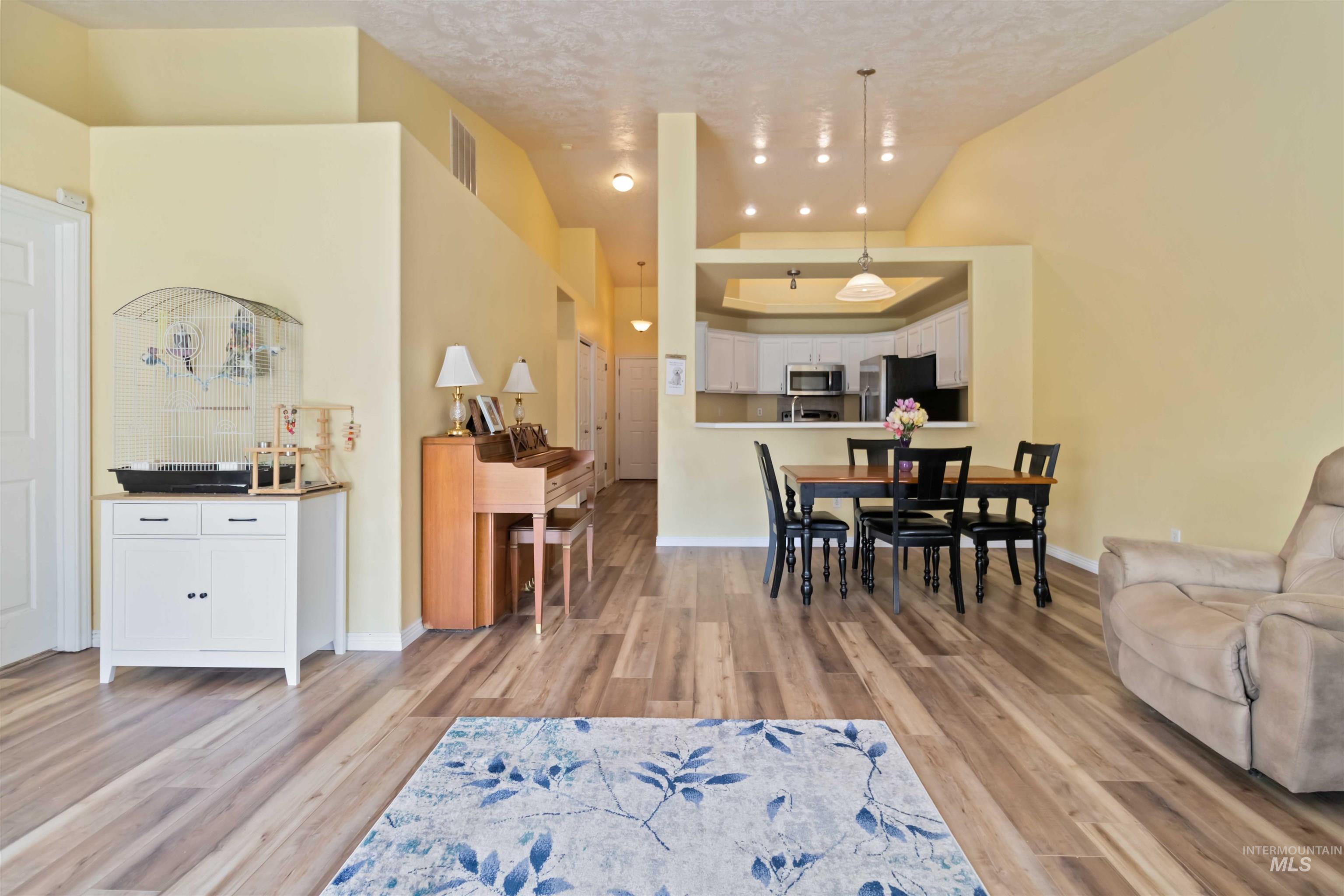 Dining room featuring light wood finished floors, a textured ceiling, and vaulted ceiling