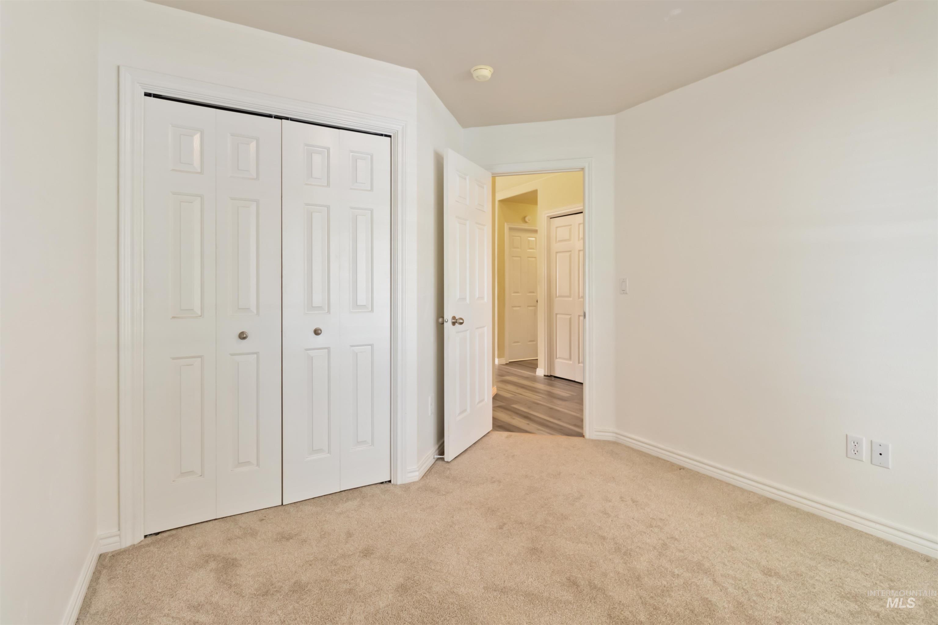 Unfurnished bedroom featuring light carpet and a closet