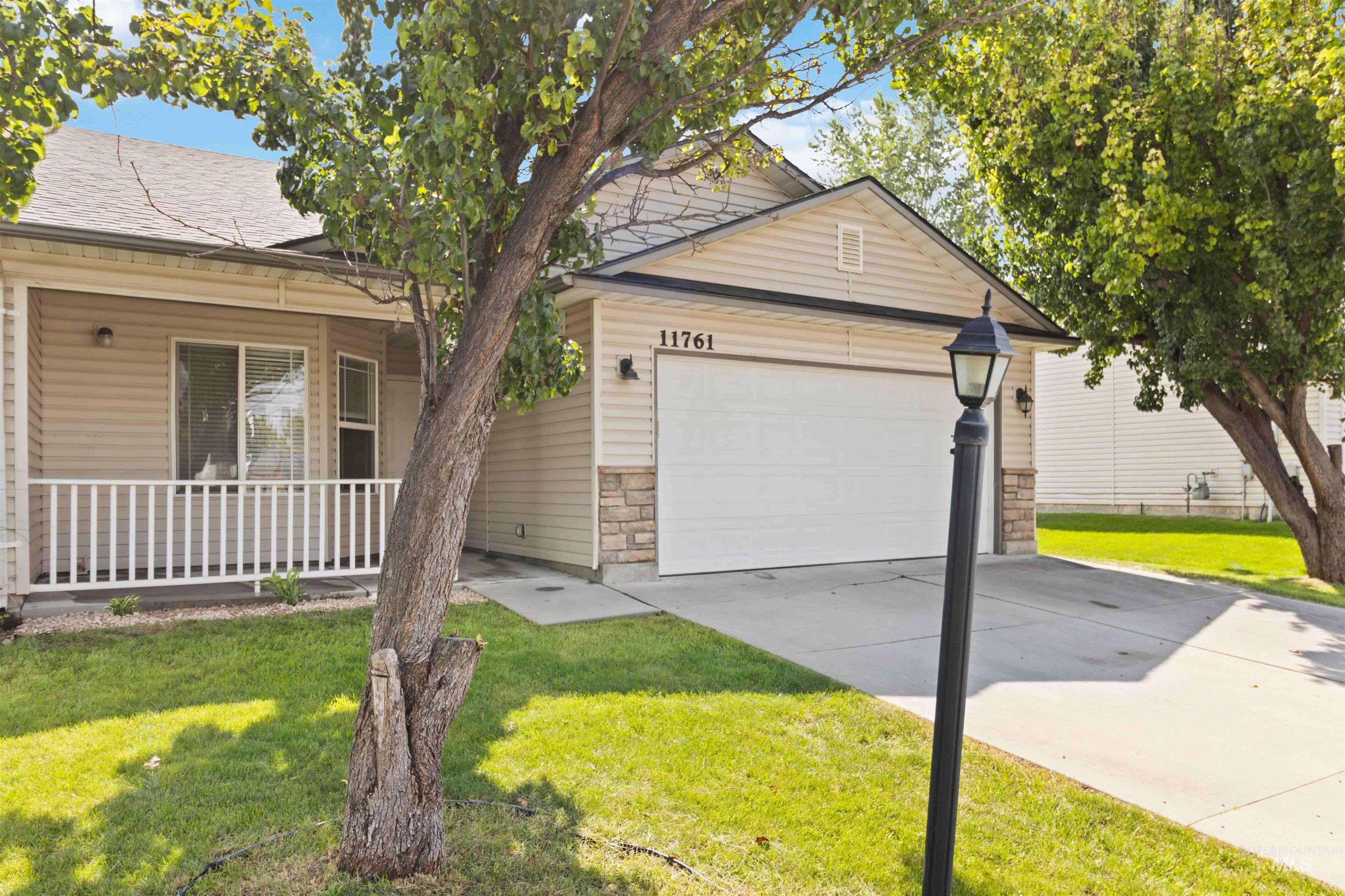 View of front facade featuring stone siding, a front lawn, concrete driveway, and an attached garage