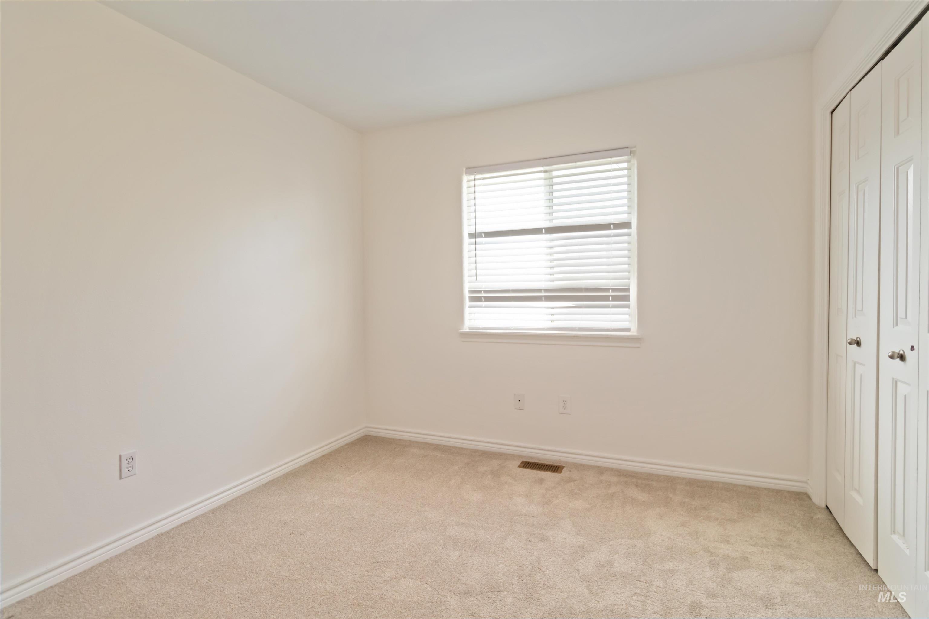 Unfurnished bedroom featuring a closet and light colored carpet