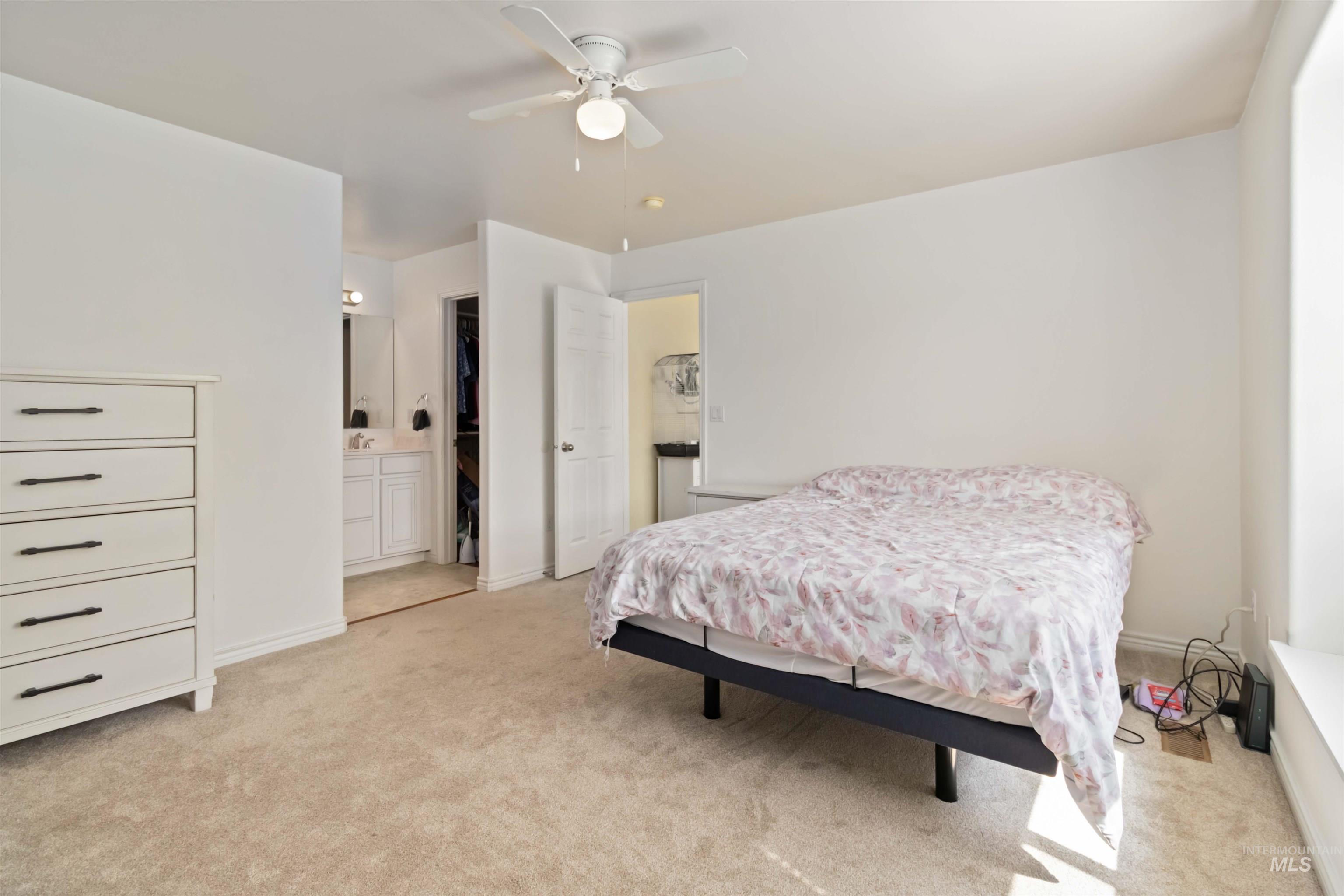Bedroom featuring light carpet, connected bathroom, and a ceiling fan