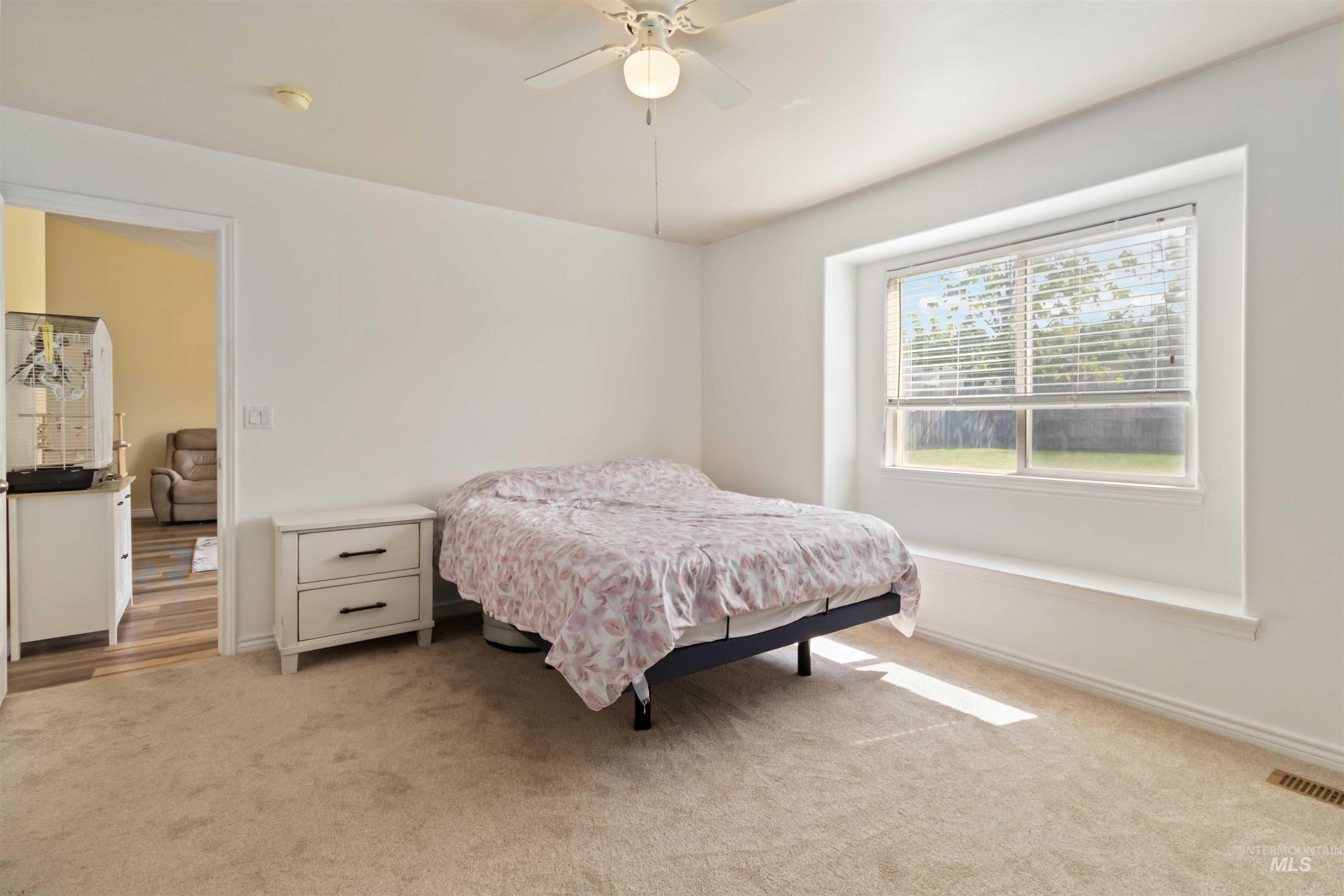 Bedroom with light colored carpet and ceiling fan
