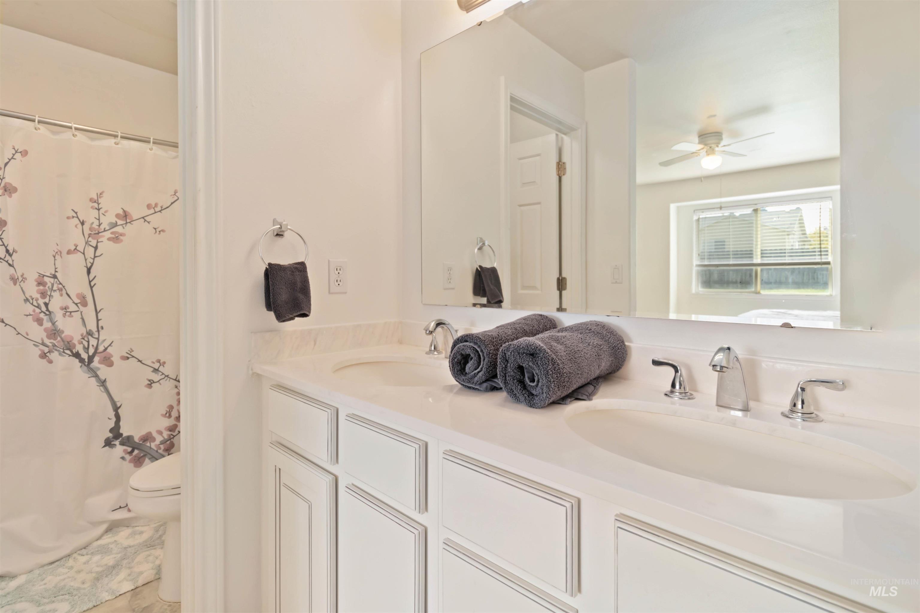 Full bath with double vanity and a ceiling fan