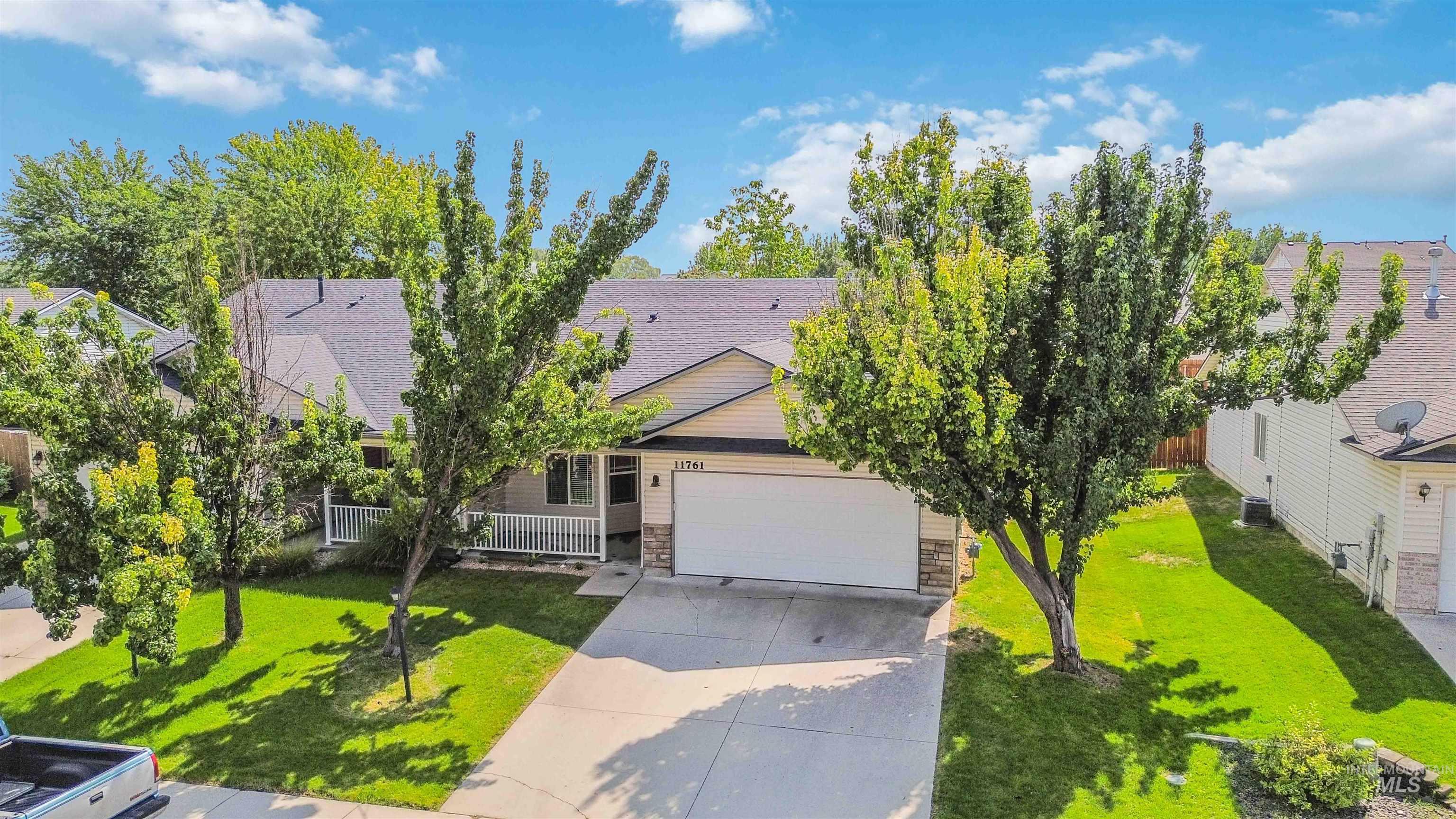 Obstructed view of property with a garage, stone siding, concrete driveway, roof with shingles, and a residential view