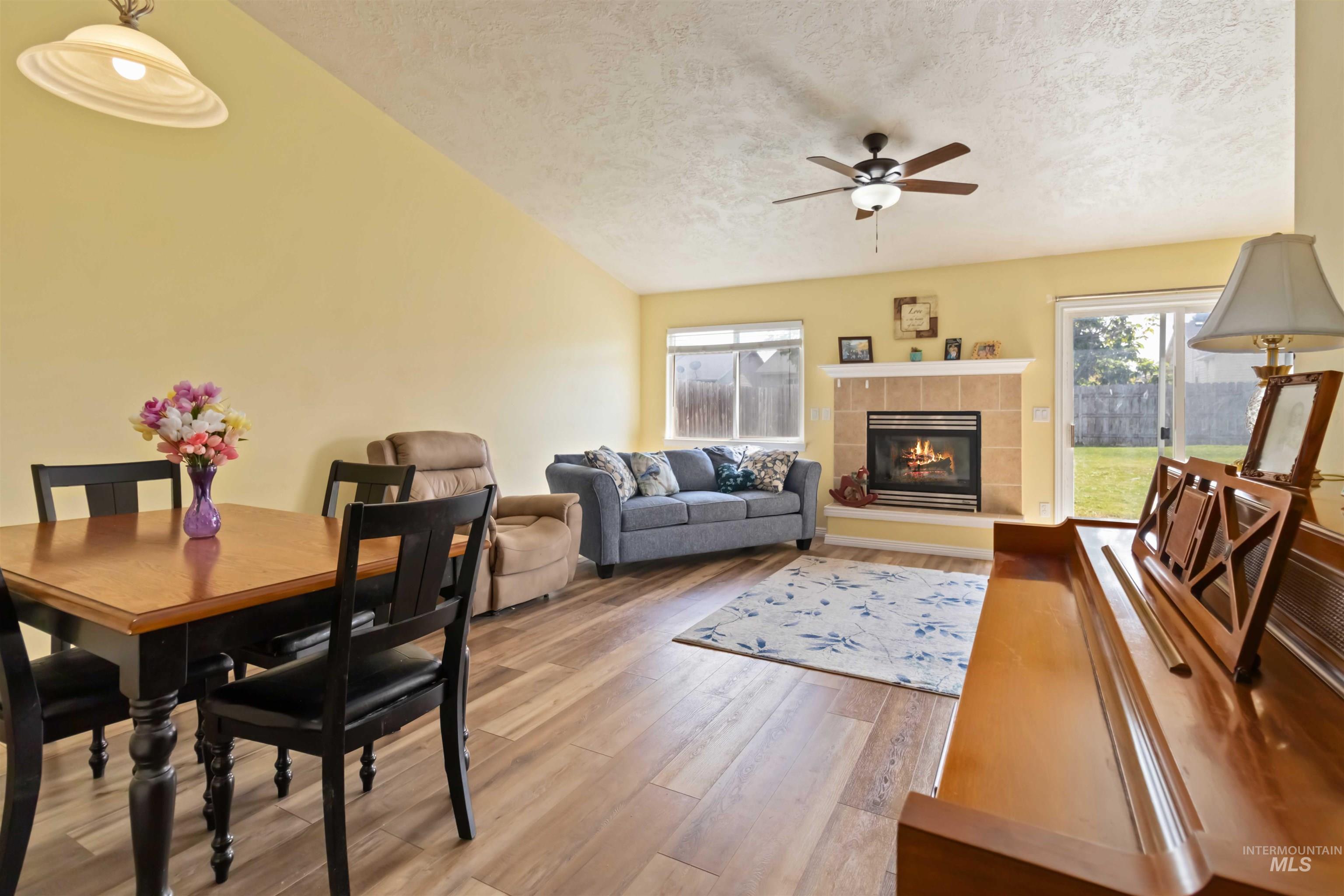 Dining area featuring a textured ceiling, a tile fireplace, light wood-style floors, and ceiling fan