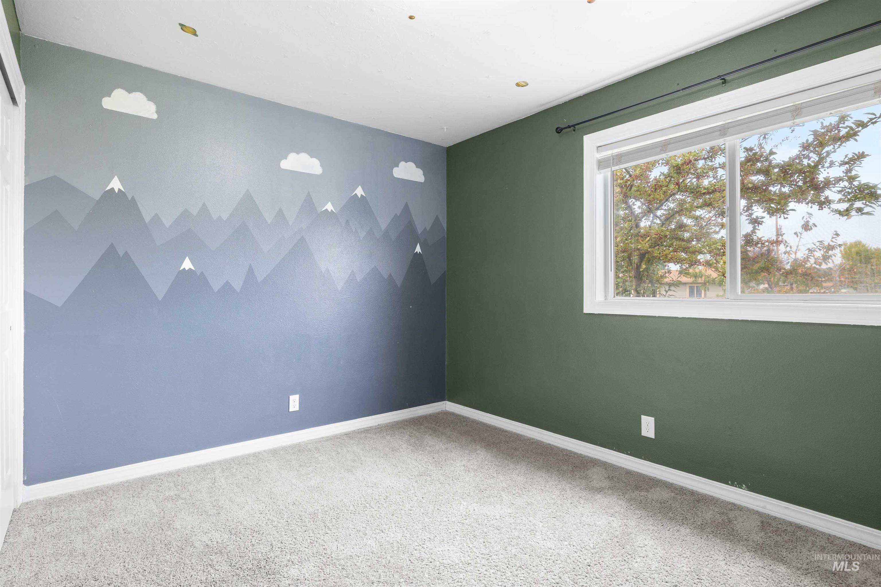Carpeted spare room featuring baseboards
