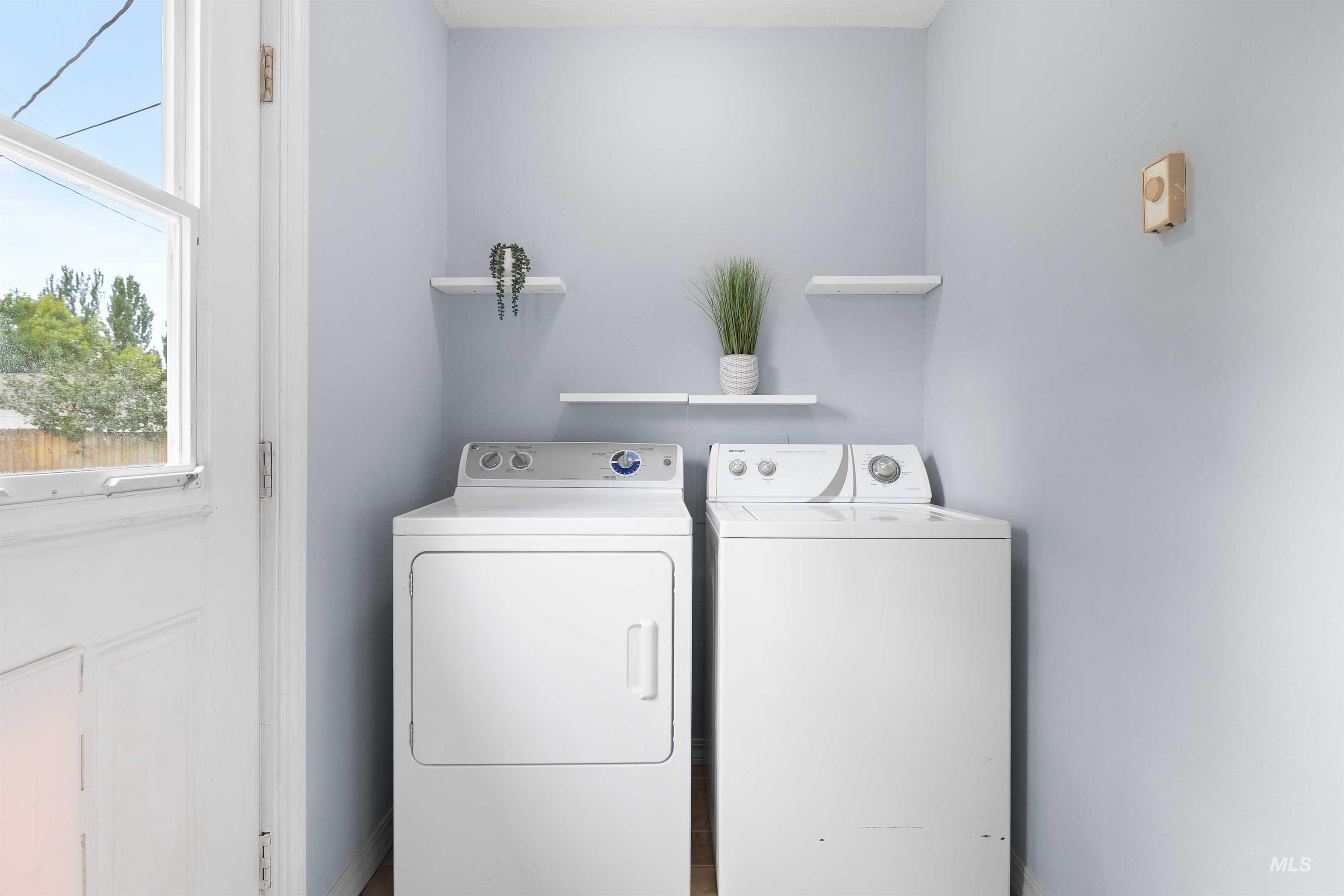 Washroom with washing machine and clothes dryer and baseboards