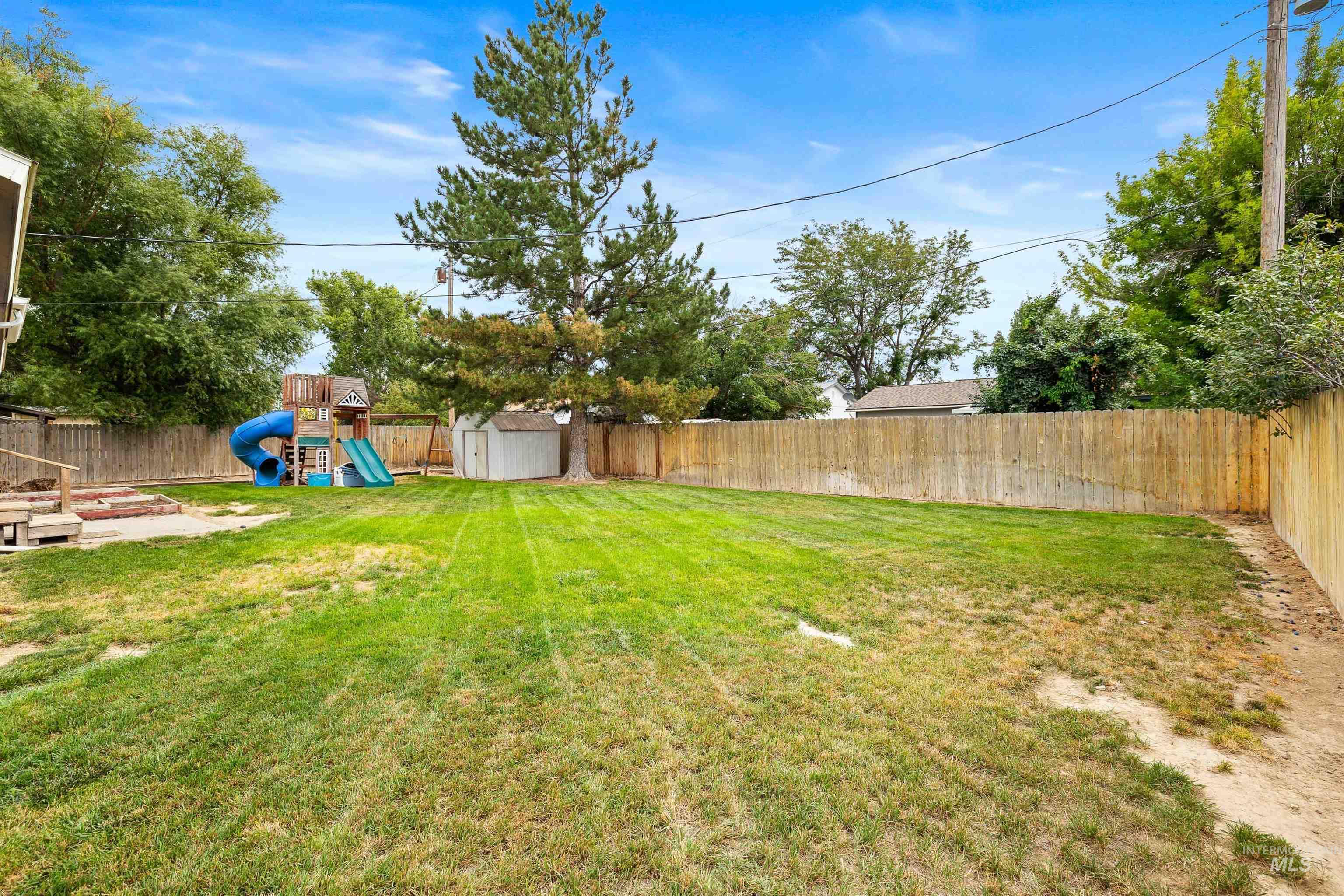 Fenced backyard featuring a playground