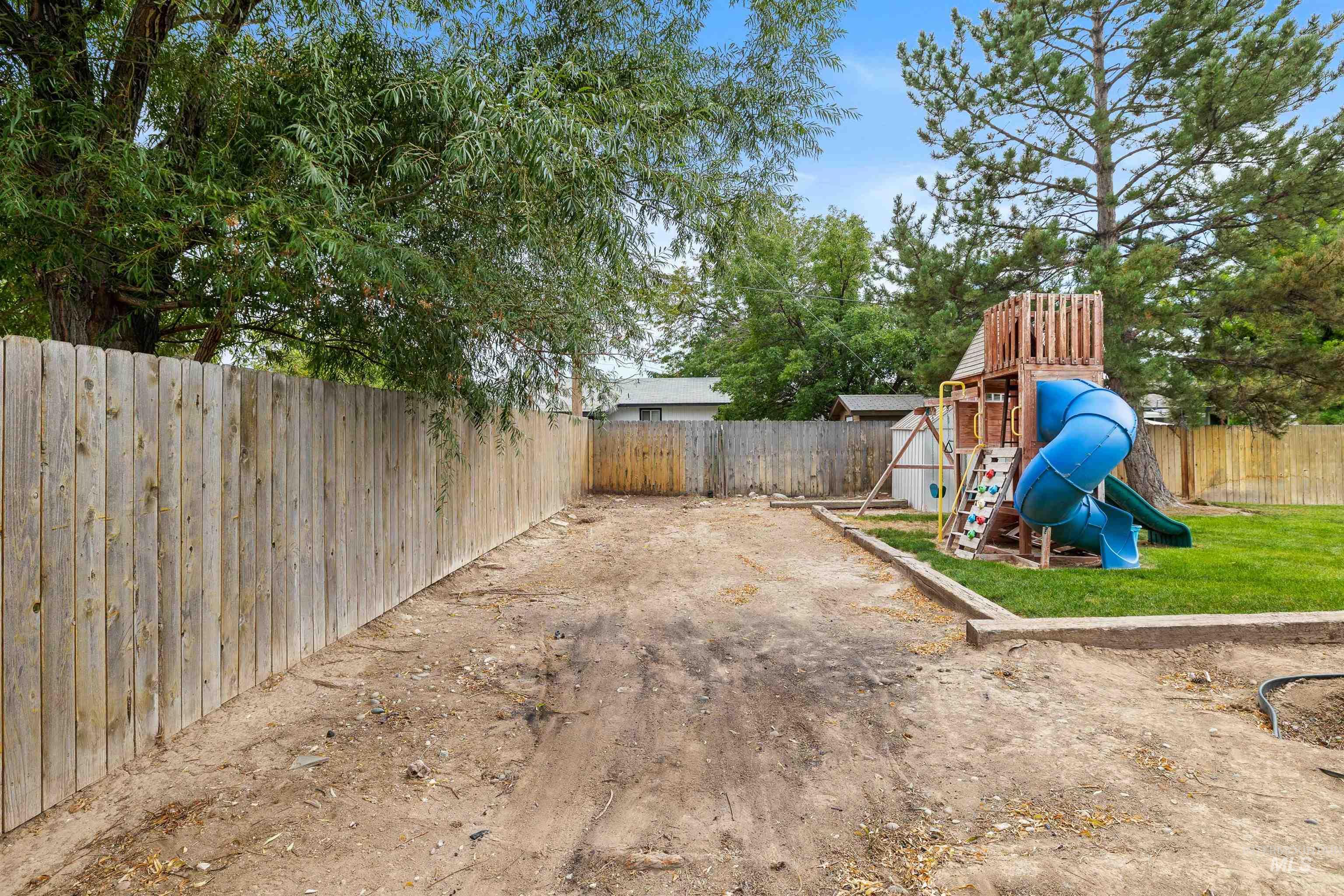 Fenced backyard featuring a playground