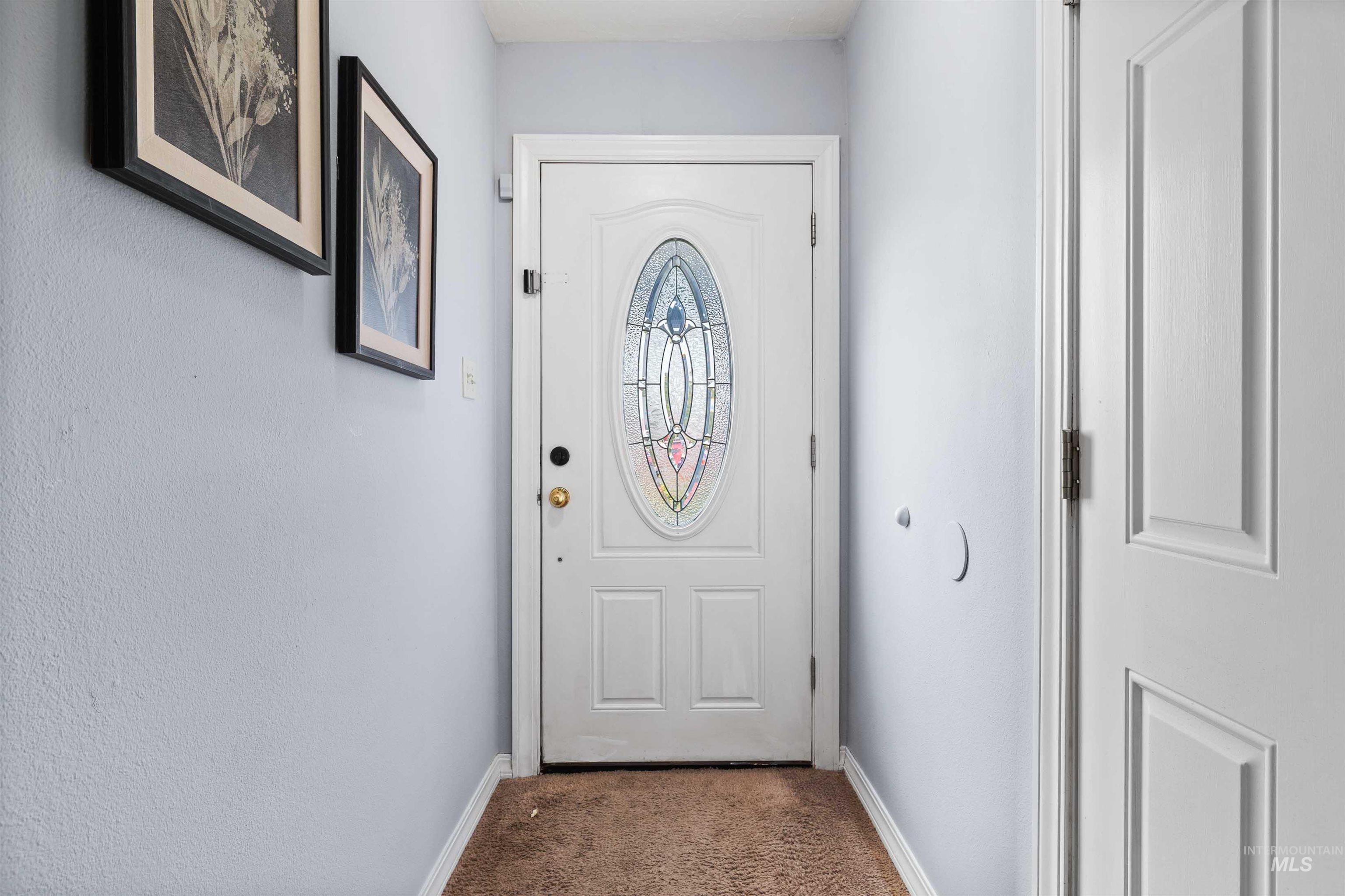 Doorway featuring baseboards and carpet flooring