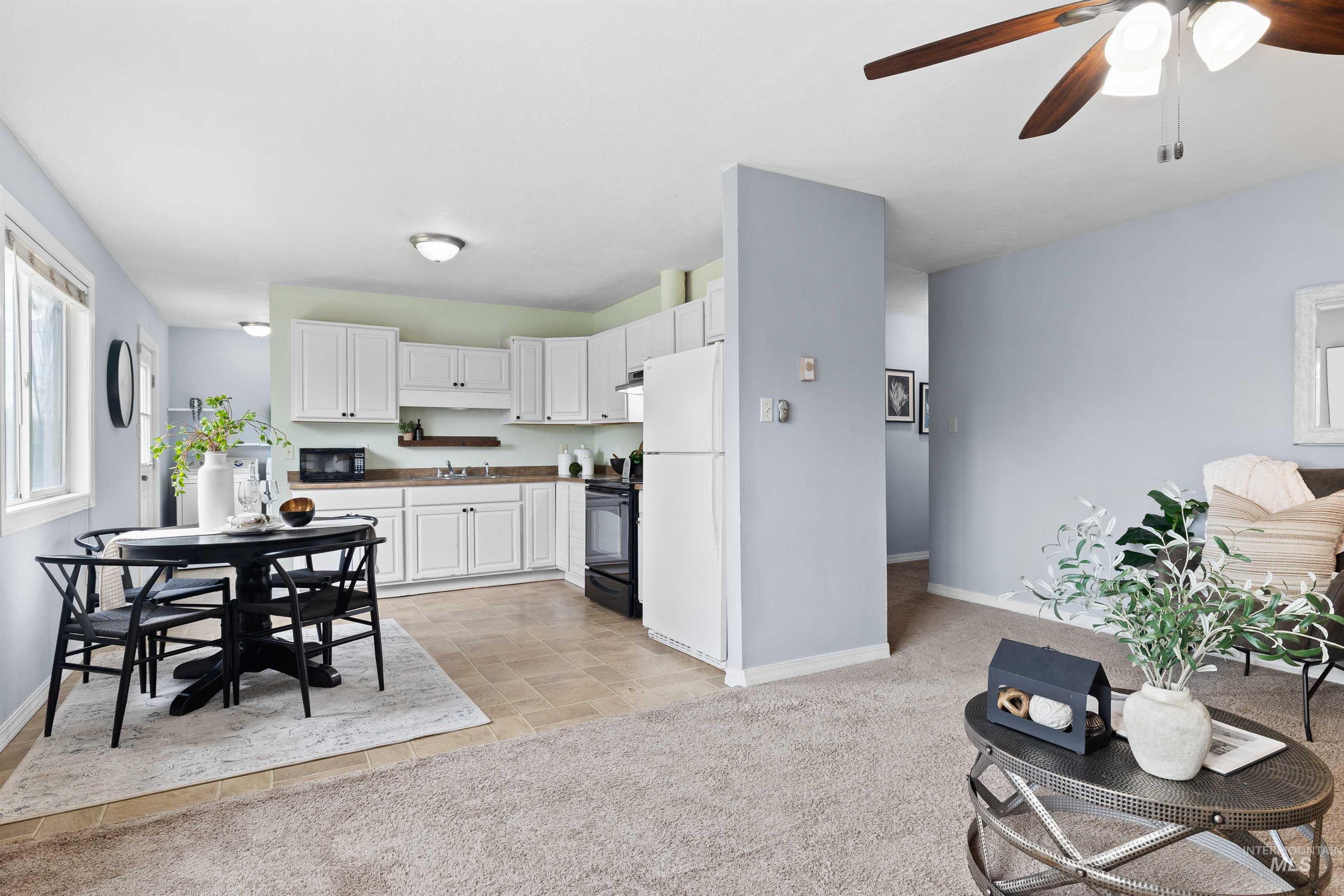 Kitchen featuring white cabinetry, ceiling fan, black appliances, light carpet, and dark countertops
