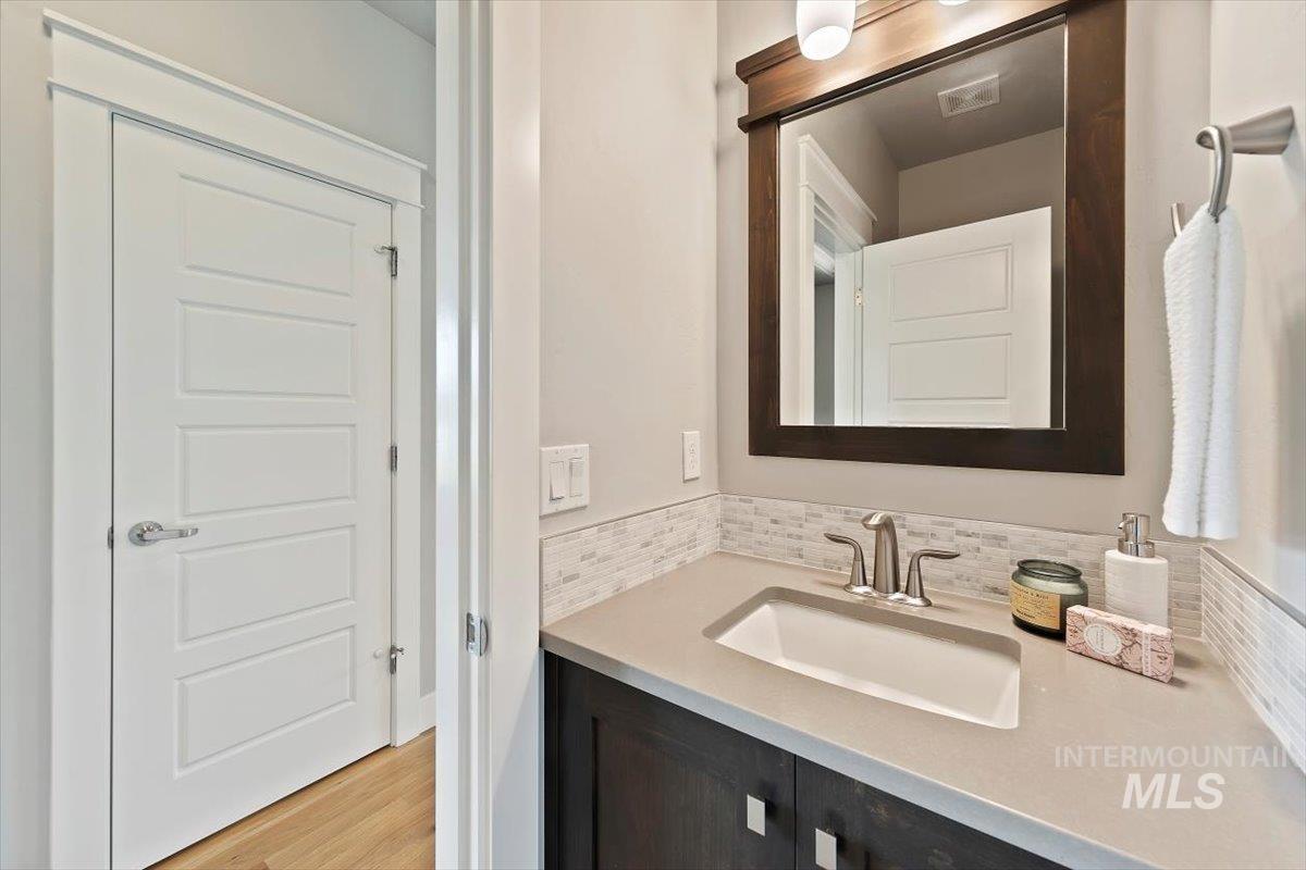 Bathroom featuring vanity, light wood finished floors, and decorative backsplash