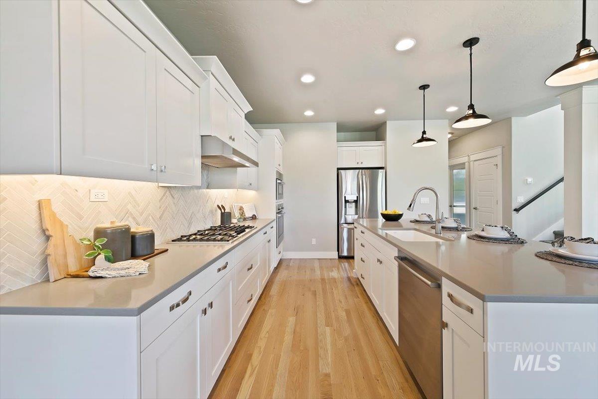 Kitchen with light wood-style floors, white cabinetry, pendant lighting, stainless steel appliances, and recessed lighting